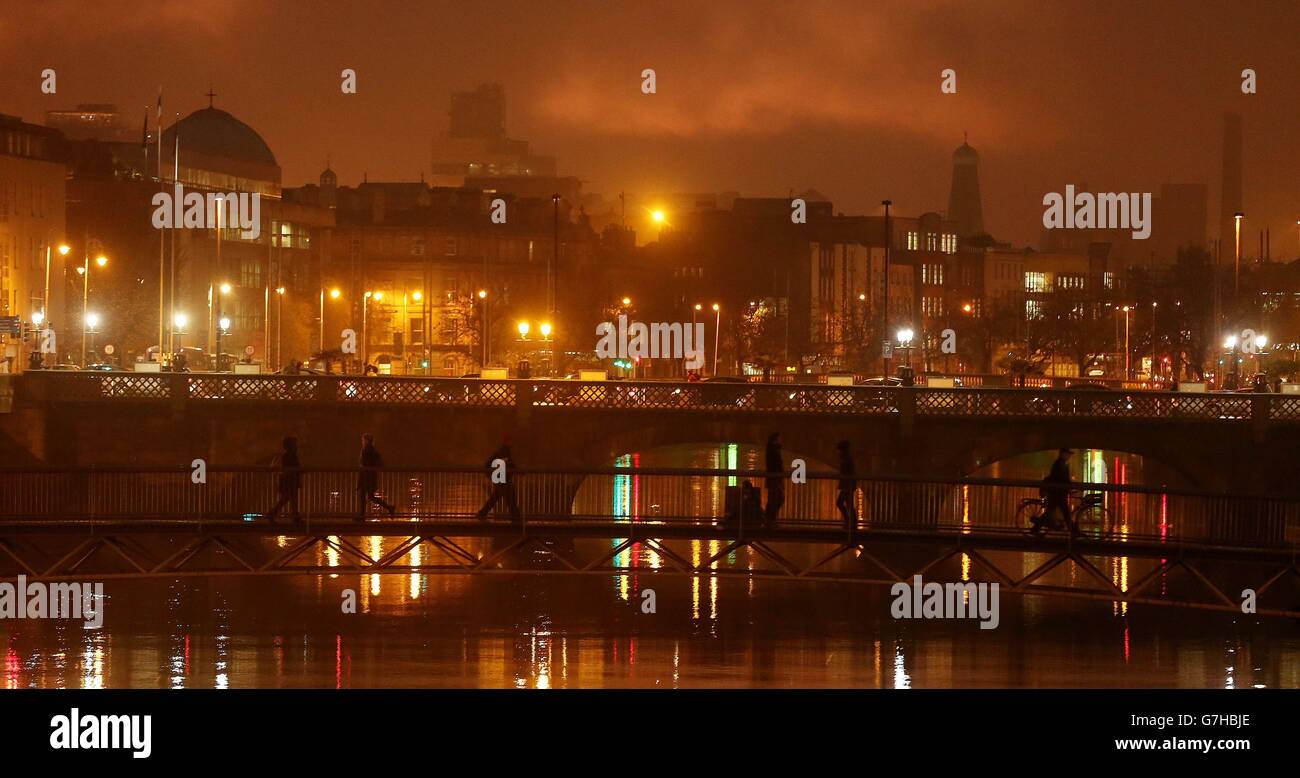 La gente attraversa il fiume Liffey a Dublino durante un periodo di nebbia invernale, come uno status arancione allarme meteo nazionale è stato emesso da Met &Eacute;ireann, prevedendo che la fitta nebbia persisterà fino alla sera. Foto Stock