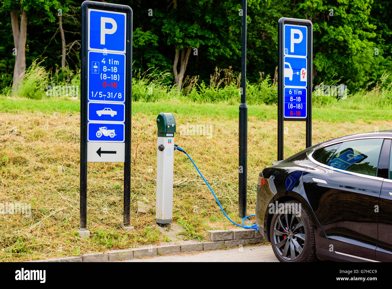 Soderkoping, Svezia - 20 Giugno 2016: pubblico stazione di ricarica per auto elettriche in uso da parte di nero auto Tesla. Segnaletica indica a abou Foto Stock