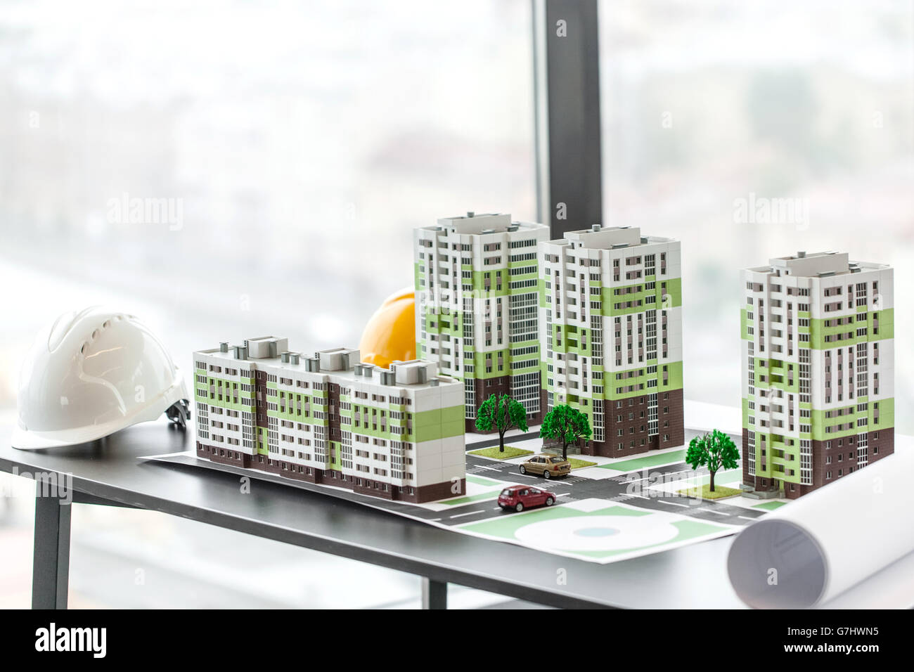 Il modello del quartiere residenziale e hardhats sul tavolo in ufficio Foto Stock