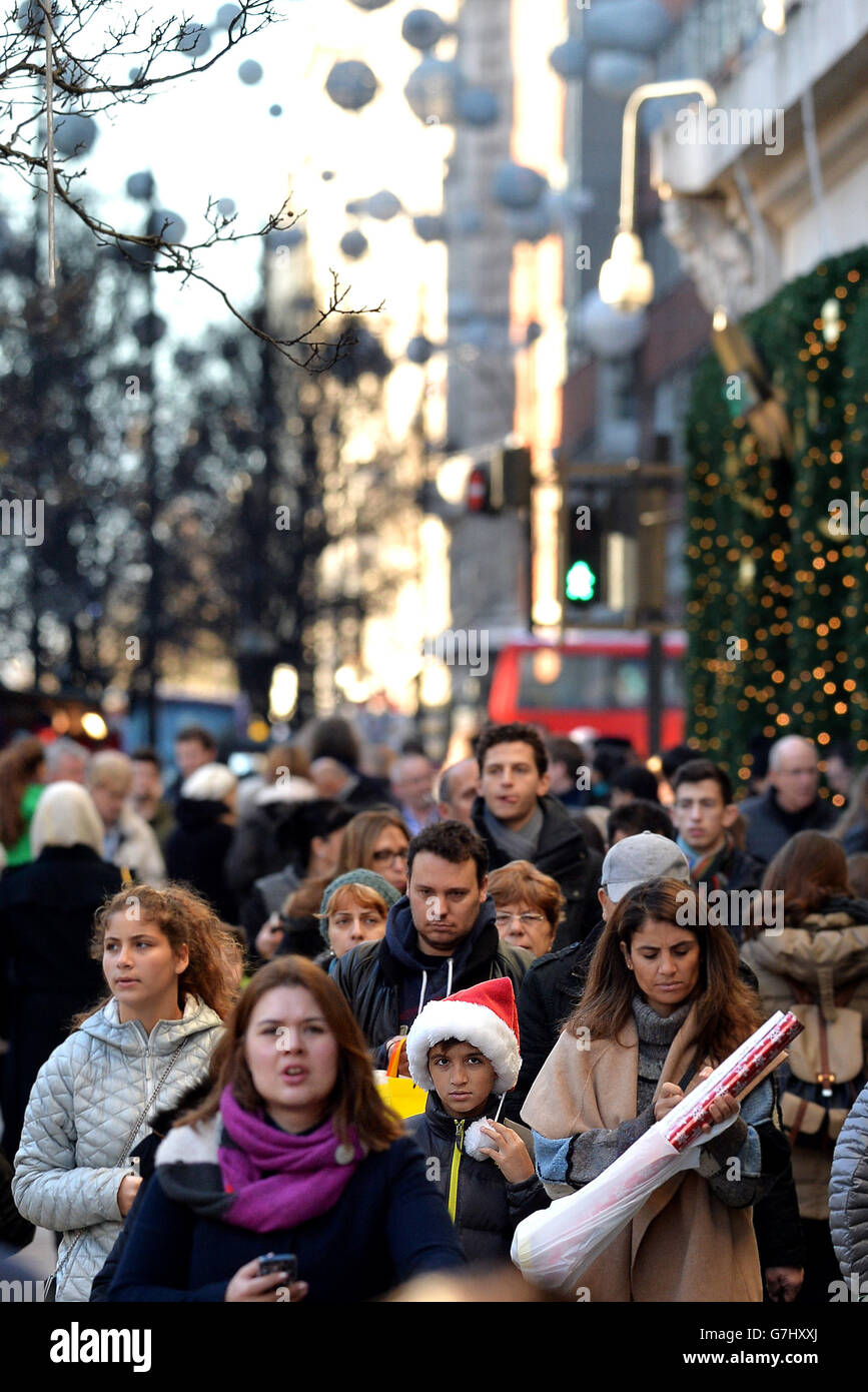 I clienti si fanno strada lungo Oxford Street con i loro regali di Natale per i loro cari, nel centro di Londra. Foto Stock