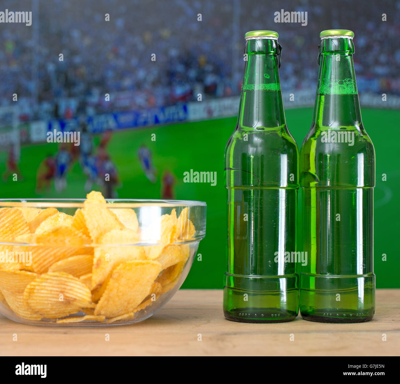 La birra e i chip nella parte anteriore della TV con la partita di calcio. Foto Stock