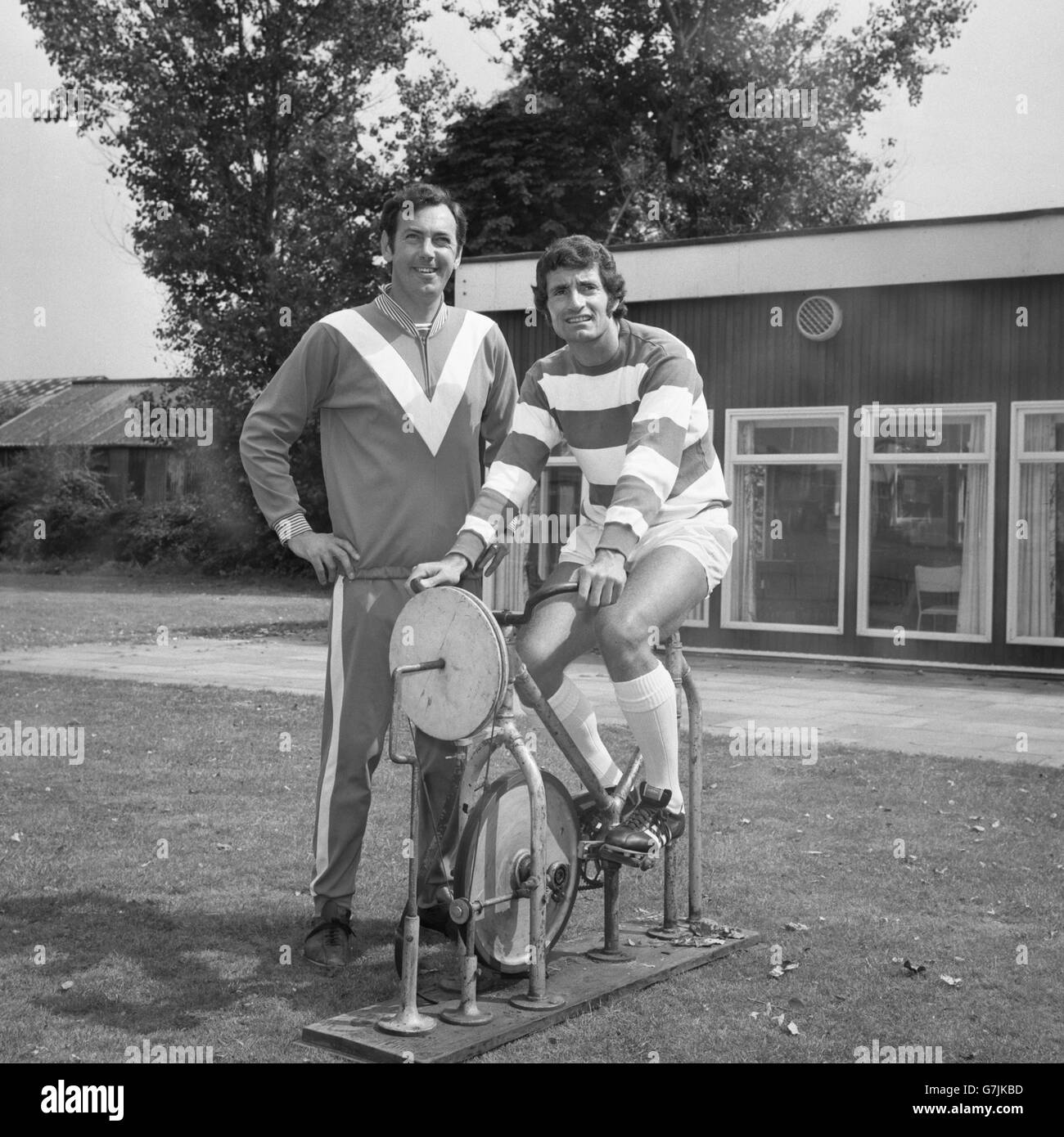 Queens Park Rangers nuovo firma Frank McLintock pedali su una bici da ginnastica al campo di allenamento Ruislip QPR, sotto l'occhio vigile del manager Gordon Jago. Foto Stock