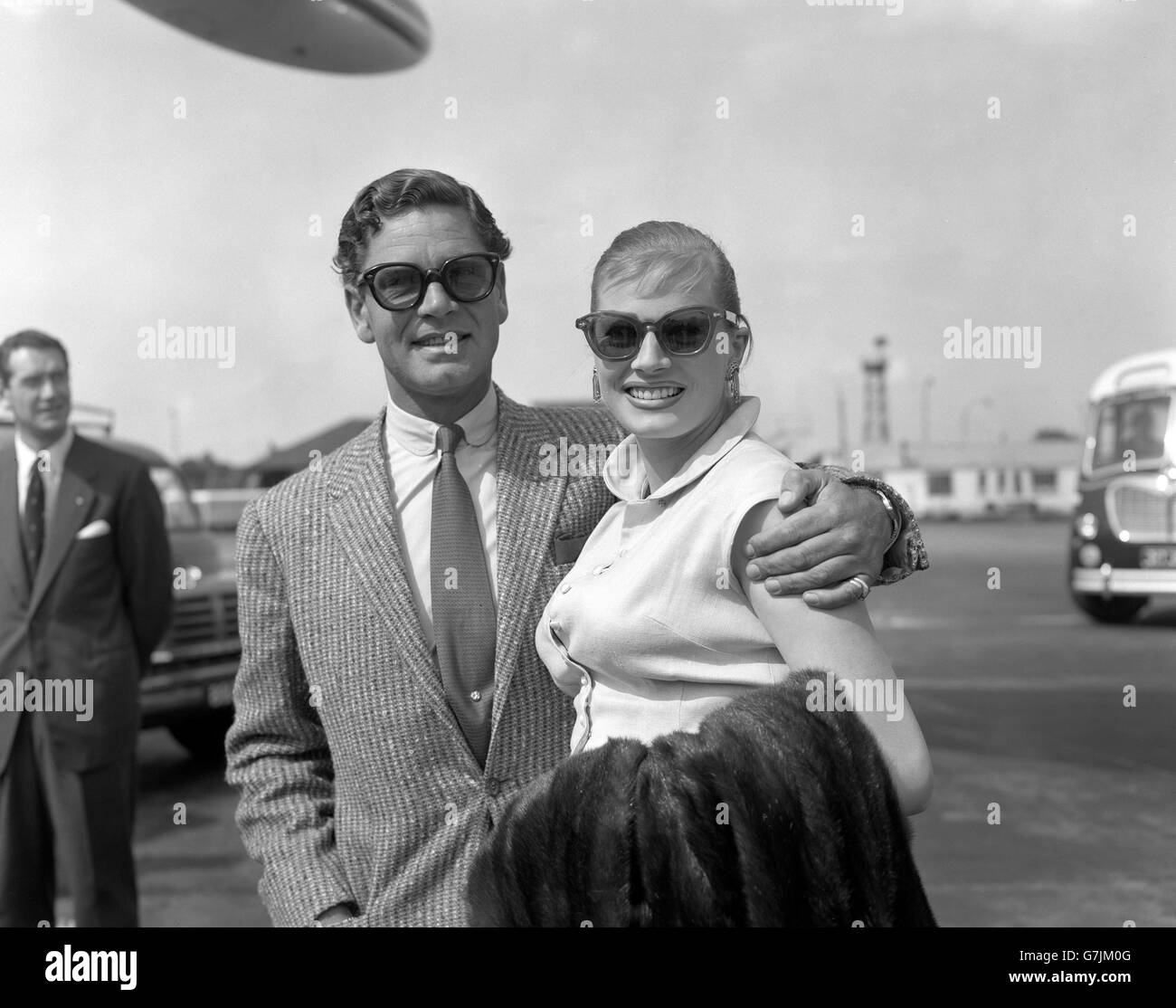 Una pettinatura con frange è indossata - con grandi occhiali da sole - dall'attrice svedese Anita Ekberg, con suo marito, attore britannico dello schermo Anthony Steel, al loro arrivo all'aeroporto di Londra da New York con TWA Liner. La sig.na Ekberg è in visita nel Regno Unito per lavorare al suo nuovo film "Interpol". Foto Stock