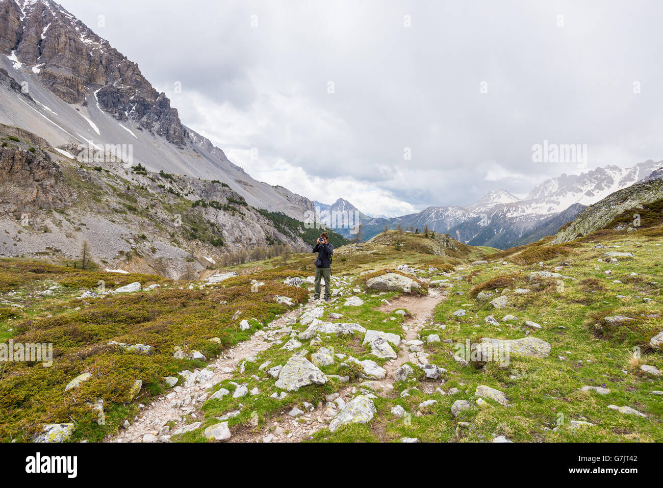 Escursionista a fotografare il paesaggio sulle montagne con drammatica Cielo e nubi. Avventure estive e di esplorazione sulle Alpi Foto Stock