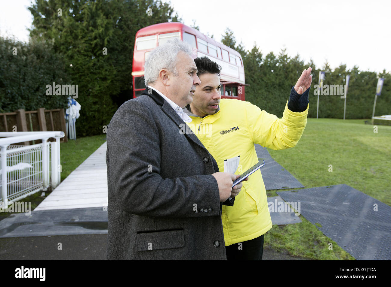 Un membro del team di benvenuto di Kempton Park accoglie i racegoisti all'ingresso Foto Stock