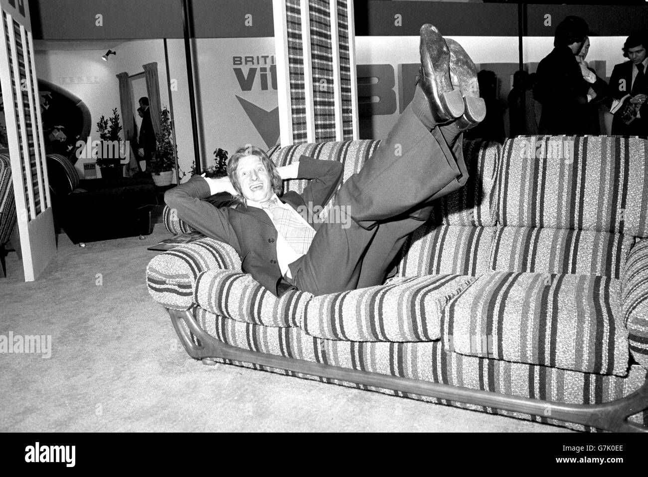 L'ex calciatore di Manchester City e Scozia, Denis Law, atterra su un divano dopo aver completato un somersault all'indietro durante l'International Furniture Show di Earls Court. Denis è il direttore di promozione delle vendite di una ditta di tappeti di Blackburn. Foto Stock