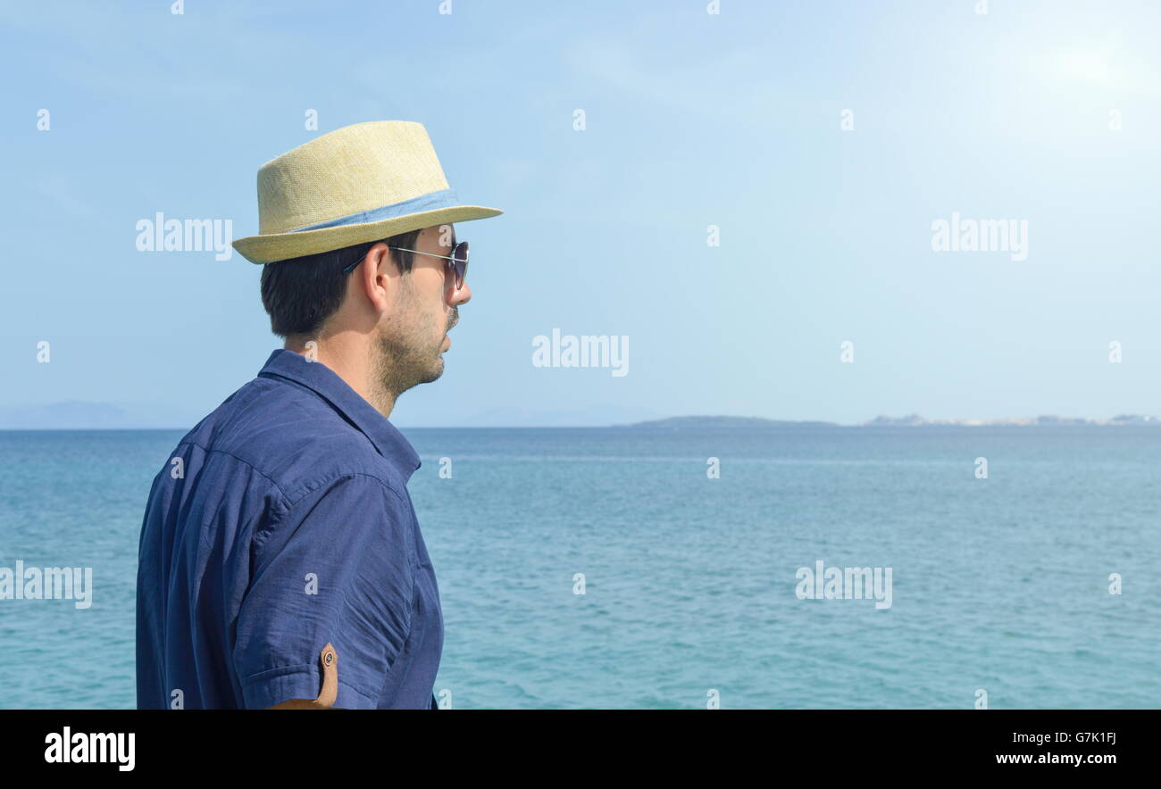 Uomo in camicia blu guardando l'orizzonte al mare Foto Stock