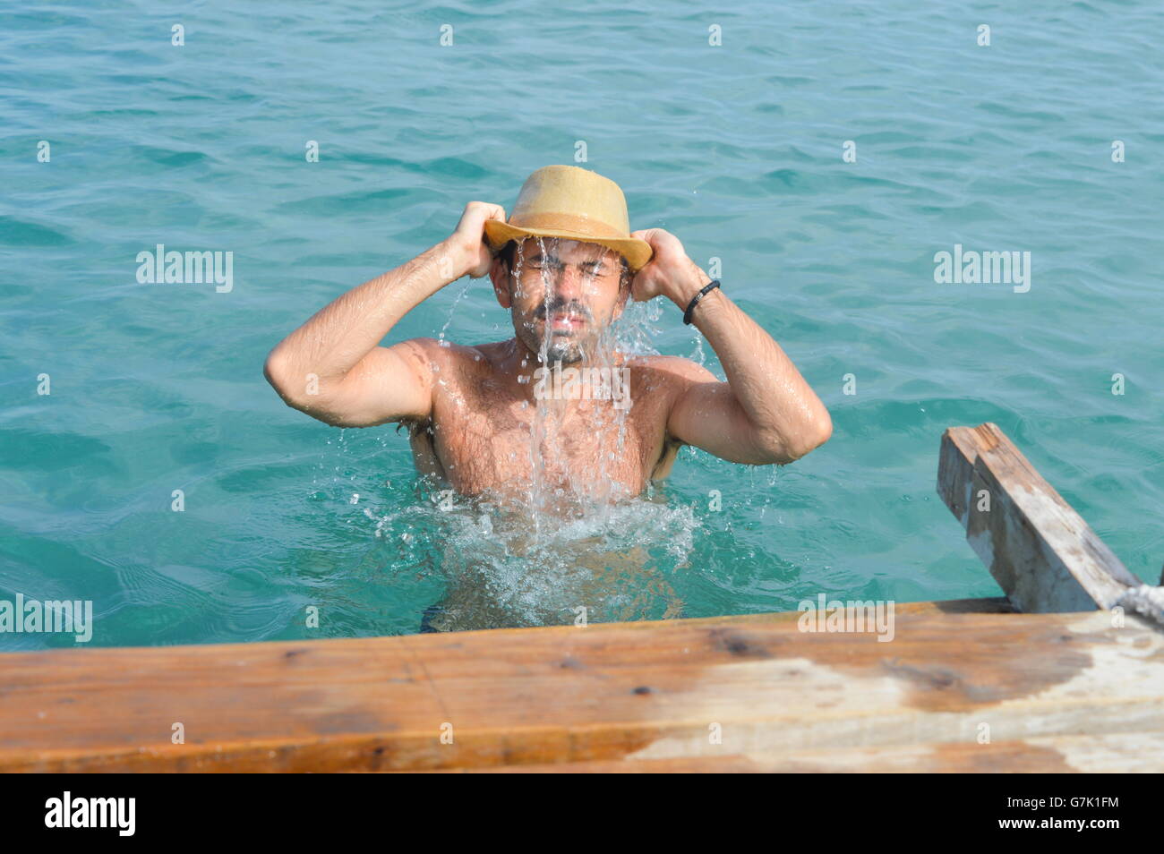 Giovane uomo in acqua di mare indossando un cappello pieno di acqua Foto Stock