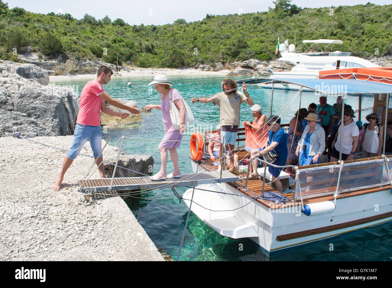 Anziani passeggero femmina essendo aiutato off crociera turistica barca sulla piccola isola di AntiPaxos, la Grecia per una gita di un giorno da Paxos Foto Stock