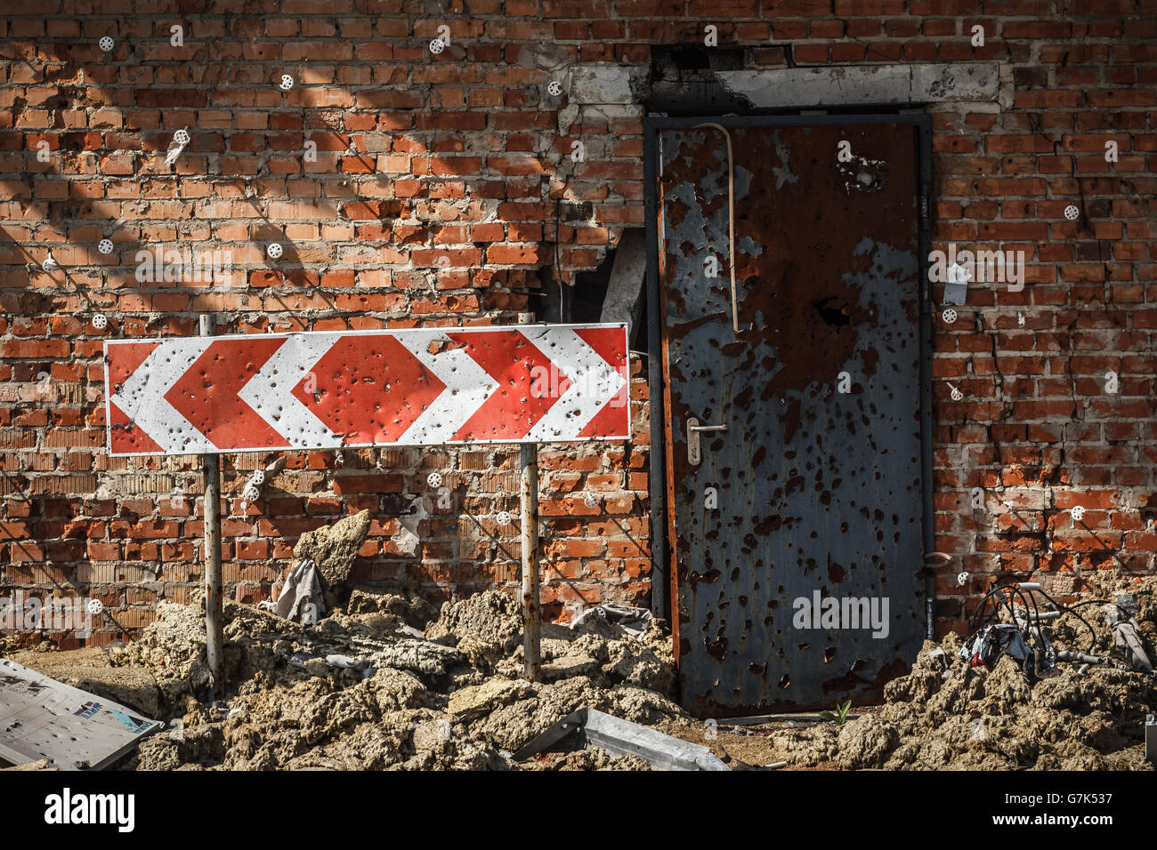 Chiazzata shrapnel con un muro di mattoni, porta e firmare Foto Stock