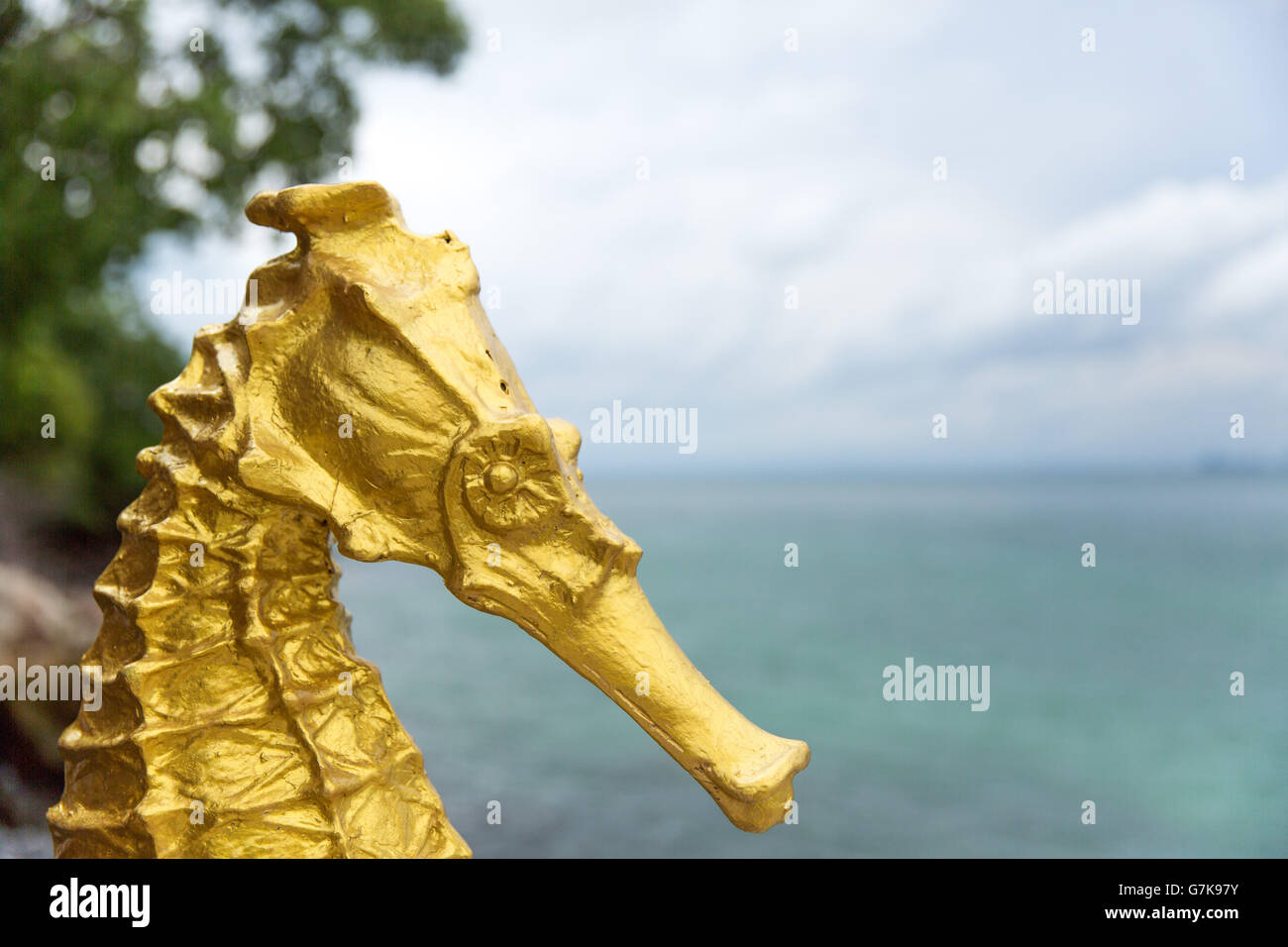 Golden cavalluccio scultura con alberi e sullo sfondo del mare Foto Stock