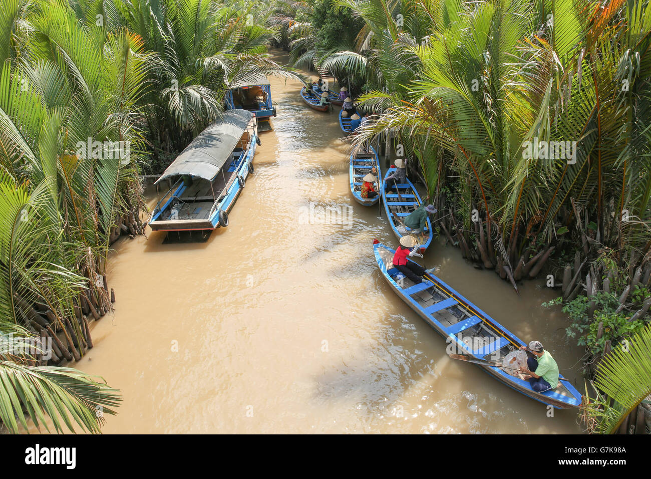 Piccole imbarcazioni in attesa di prelevare i turisti lungo il fiume fangoso nel Delta del Mekong in Vietnam Foto Stock