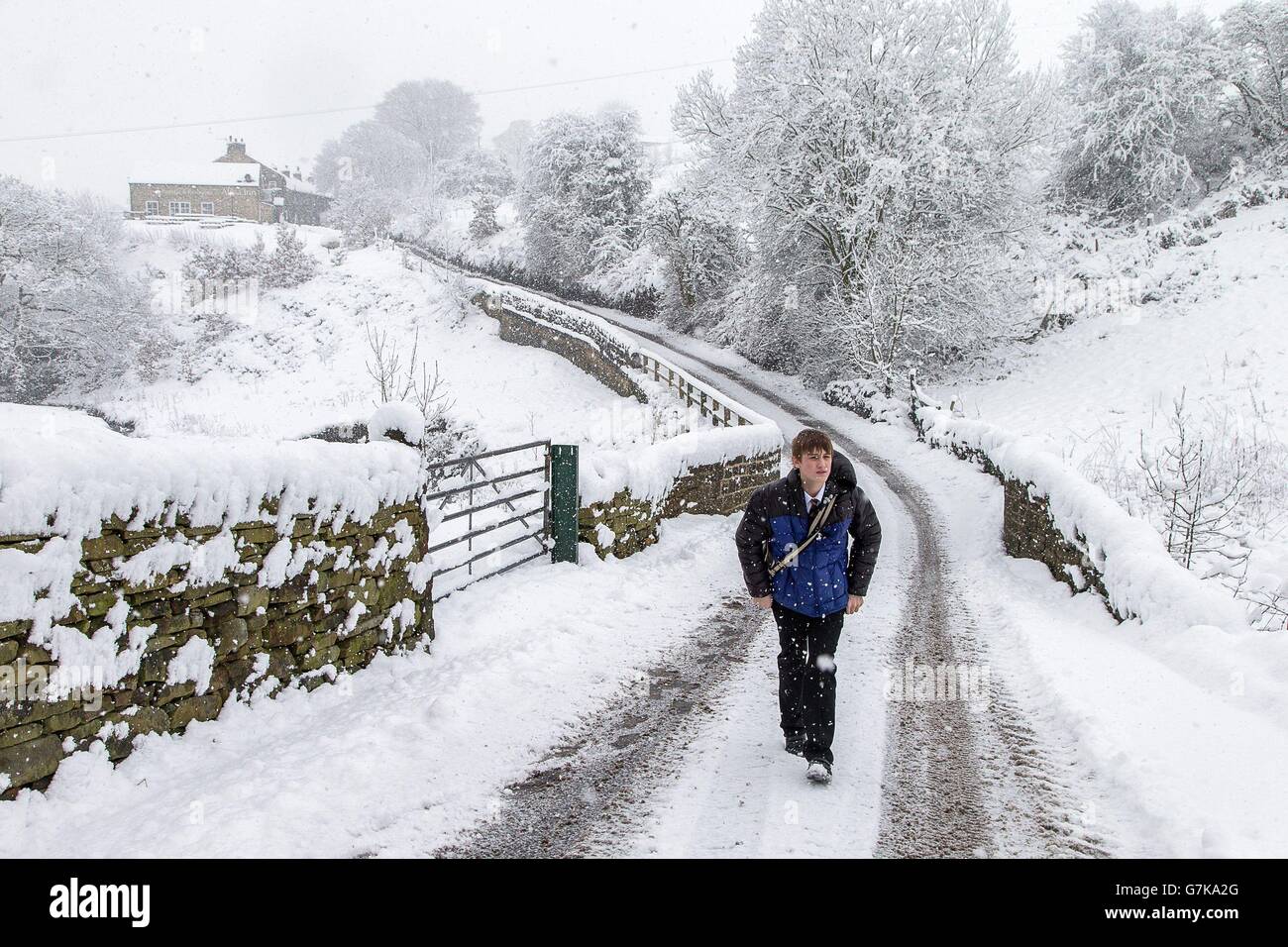 Un allievo della Ryburn Valley High School cammina a casa passando l'Alma Inn a Cottonstones, vicino a Halifax, West Yorkshire, dopo che la scuola è stata costretta a chiudere presto a causa del maltempo. Foto Stock