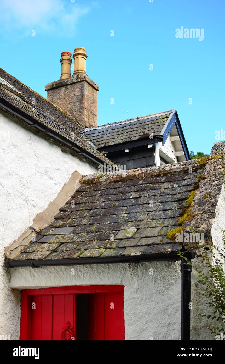 Tipici cottage scozzese con porta rossa e spiovente del tetto di ardesia nel Parco nazionale di Cairngorms Foto Stock