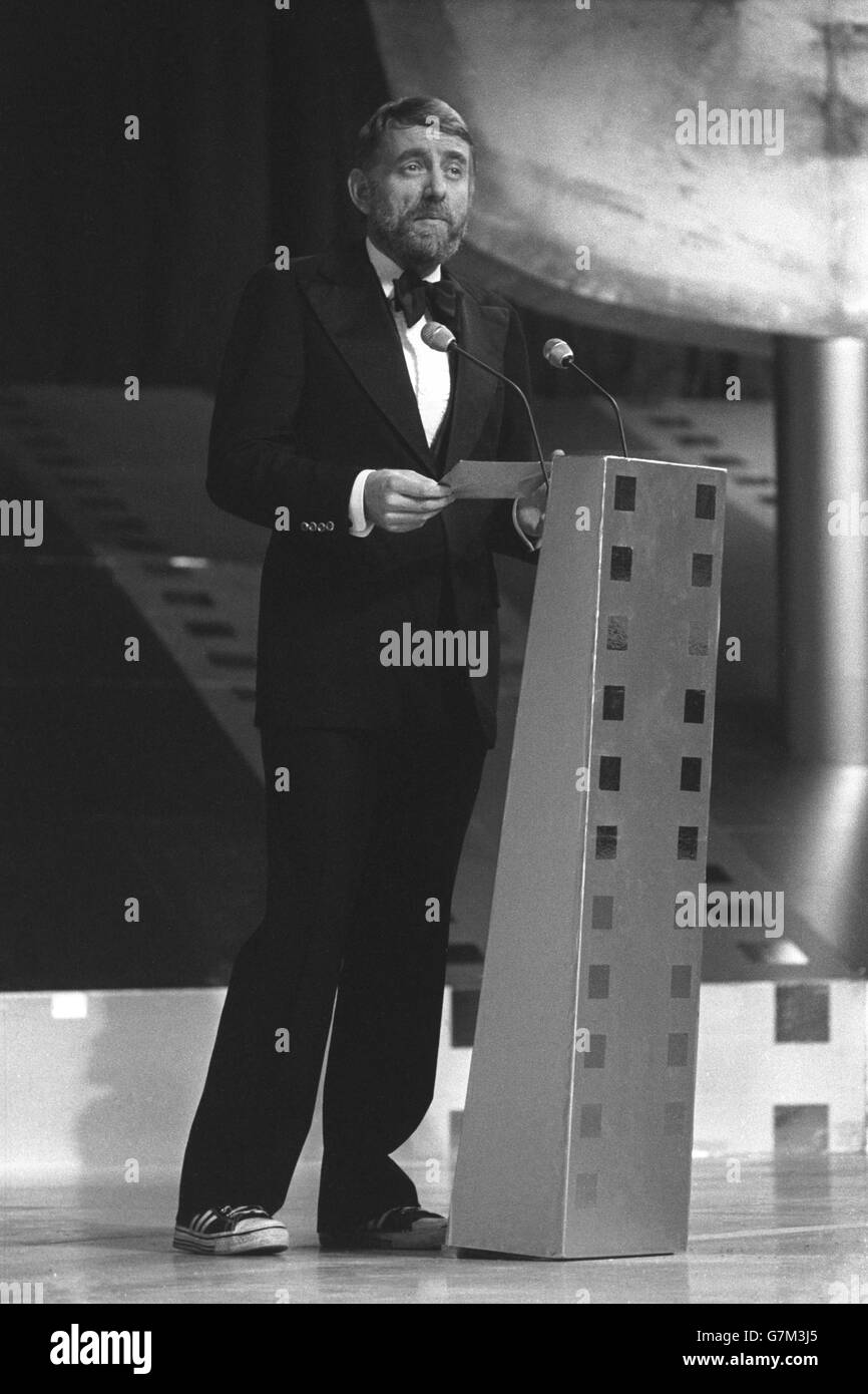 Un bow-tie e scarpe da baseball per il milionario poeta pop Rod McKuen mentre legge le nomination per l'Anthony Asquith Memorial Award durante la presentazione della British Academy of Film and Television Arts 1975 Awards alla Royal Albert Hall, Londra. Rod ha accettato il premio per conto di John Williams per il suo punteggio originale per il film 'Jaws'. Foto Stock