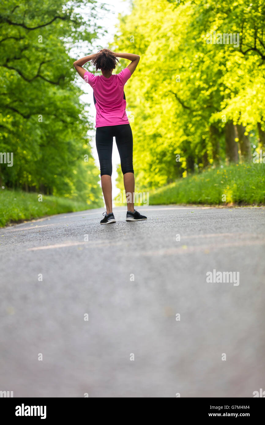 Bellissima gara di misto americano africano donna giovane ragazza adolescente in esecuzione fitness jogging in appoggio sulla strada fiancheggiata con molla o somma Foto Stock