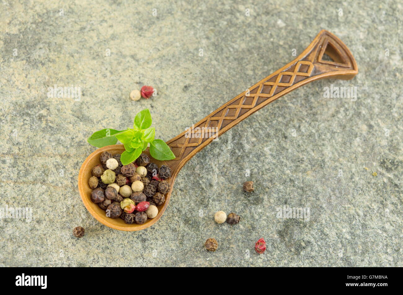 Pepe grani spezie in un cucchiaio di legno su un tavolo di pietra Foto Stock