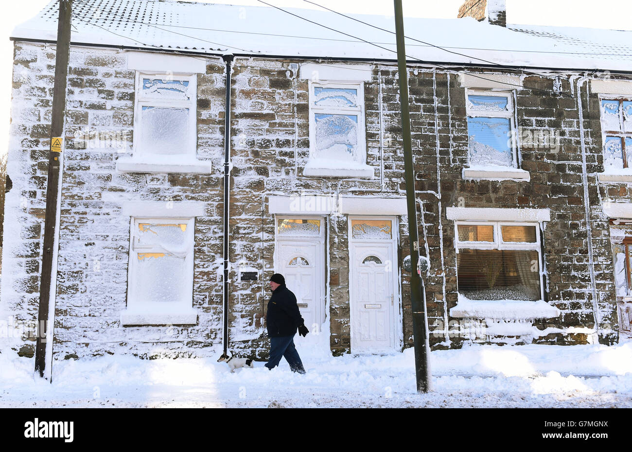 Un uomo cammina il suo cane attraverso Tow Law, County Durham dopo la neve pesante colpito la regione la notte scorsa. Foto Stock