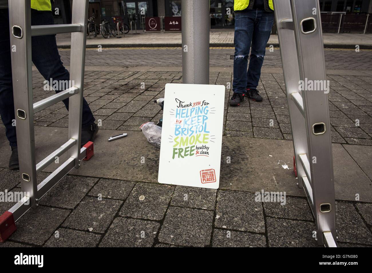 Un segno accanto ad un lampione in Millennium Square a Bristol, in quanto è uno dei due spazi pubblici per andare senza fumo come un pilota volontario è lanciato. Foto Stock