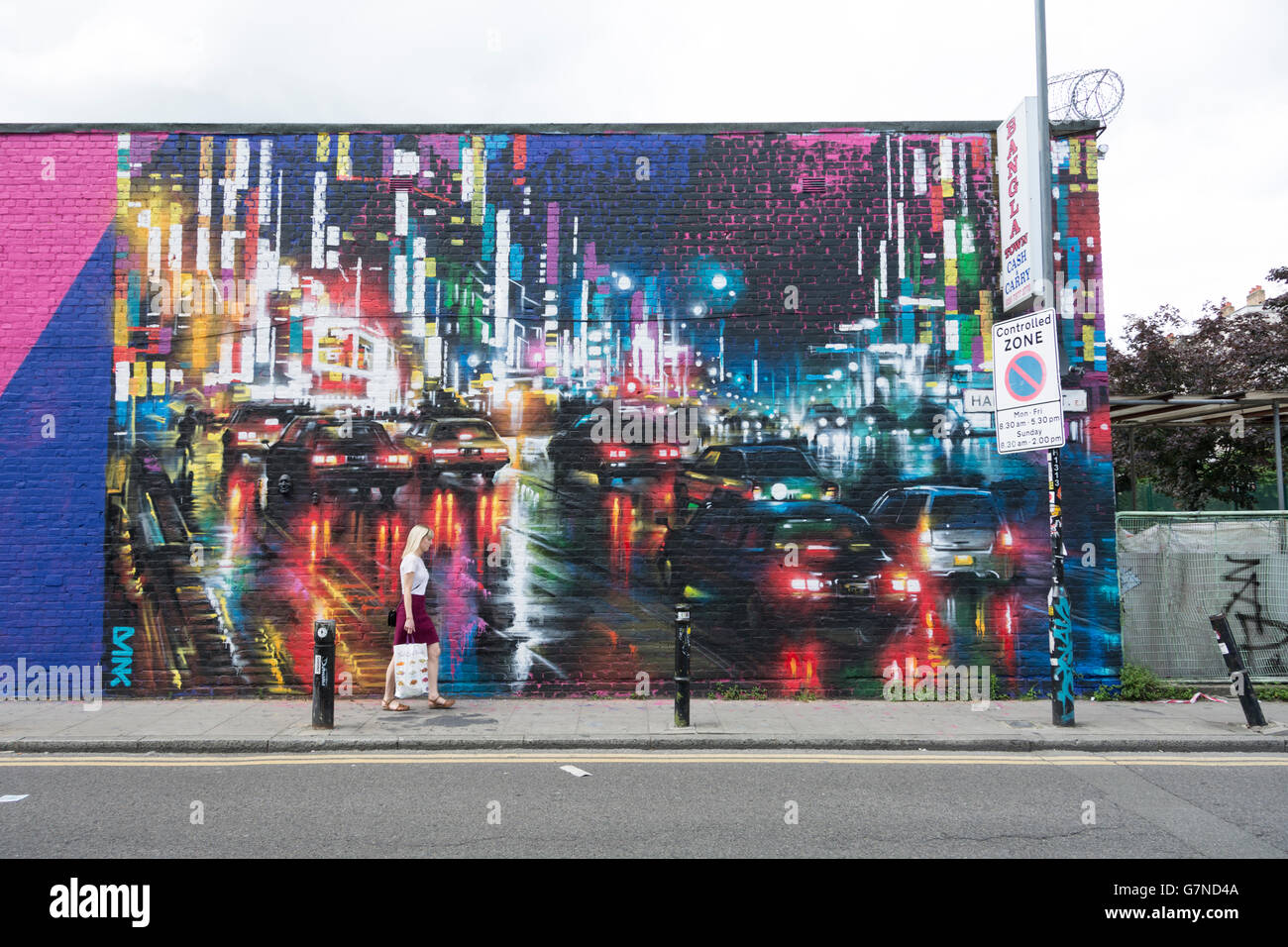 Una donna che cammina su Hanbury Street in East End di Londra. Foto Stock