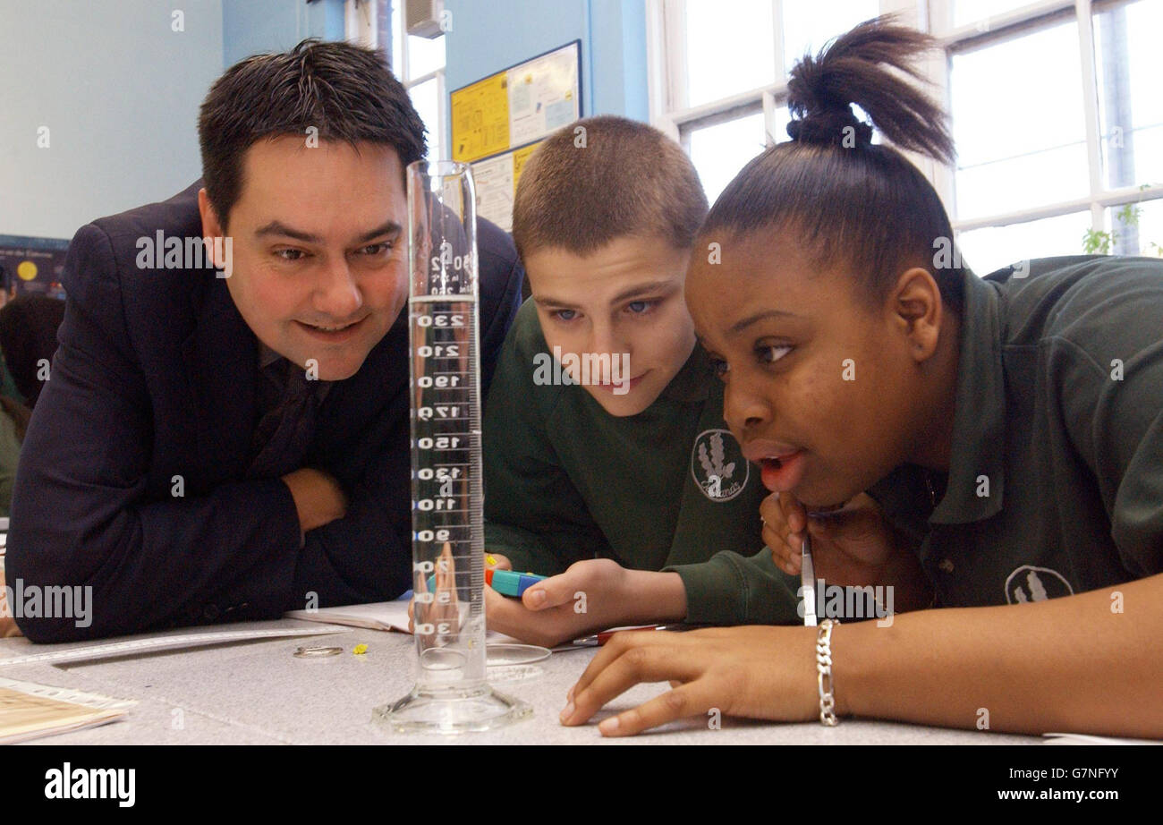 Stephen Twig, ministro degli Standard scolastici, si unisce ai 11 allievi Lee Mawbey (centro), 15 e Zuyane Russell, 16 anni, in un esperimento per misurare la velocità terminale, utilizzando un cordone di cellule styro in acqua, presso la Oaklands Secondary School. Foto Stock