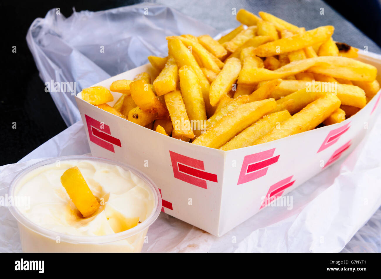 Scatola di patatine fritte accanto a una vasca di maionese. Foto Stock