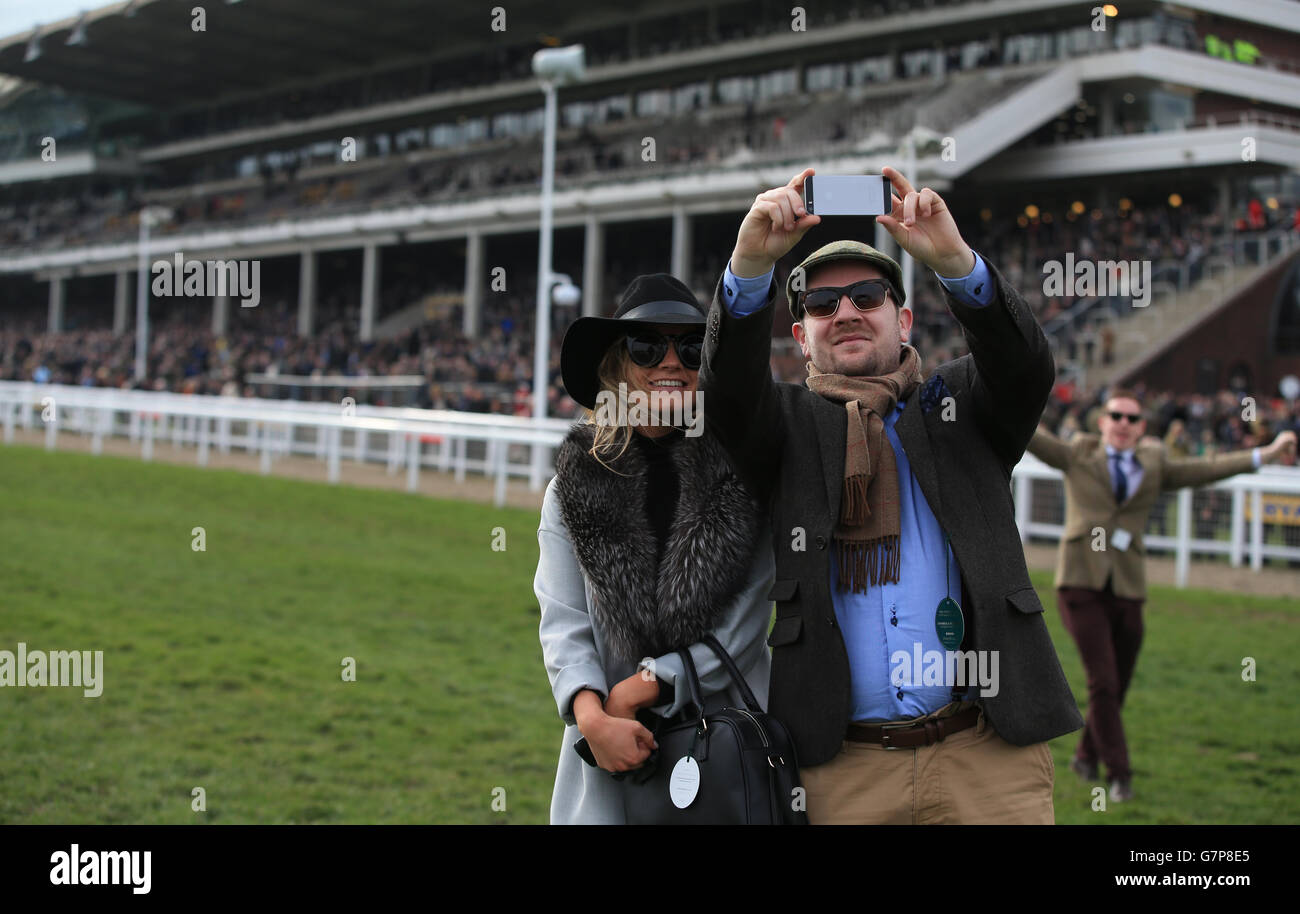 Racegoers prende una 'felfie' in pista come un fotobomber rende nota la sua presenza in background, il giorno di San Patrizio durante il Cheltenham Festival all'ippodromo di Cheltenham. PREMERE ASSOCIAZIONE foto. Data foto: Giovedì 12 marzo 2015. Vedi la storia della Pennsylvania RACING Cheltenham. Il credito dell'immagine deve essere: Nick Potts/PA Wire. Foto Stock