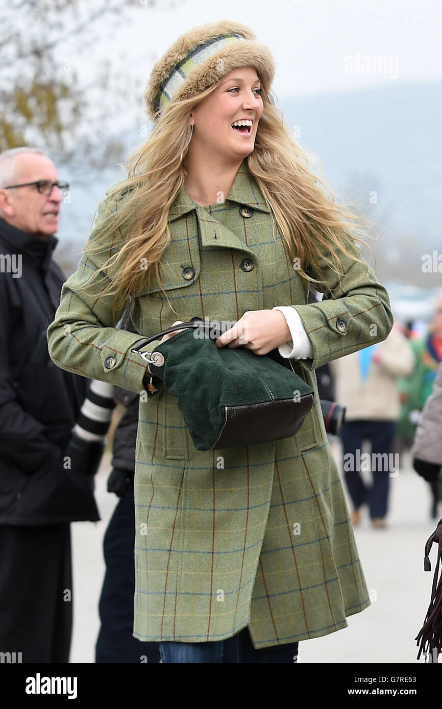 Una racegoista femminile con tweed e un cappello da pelliccia arriva il giorno di San Patrizio durante il Cheltenham Festival all'ippodromo di Cheltenham. Foto Stock