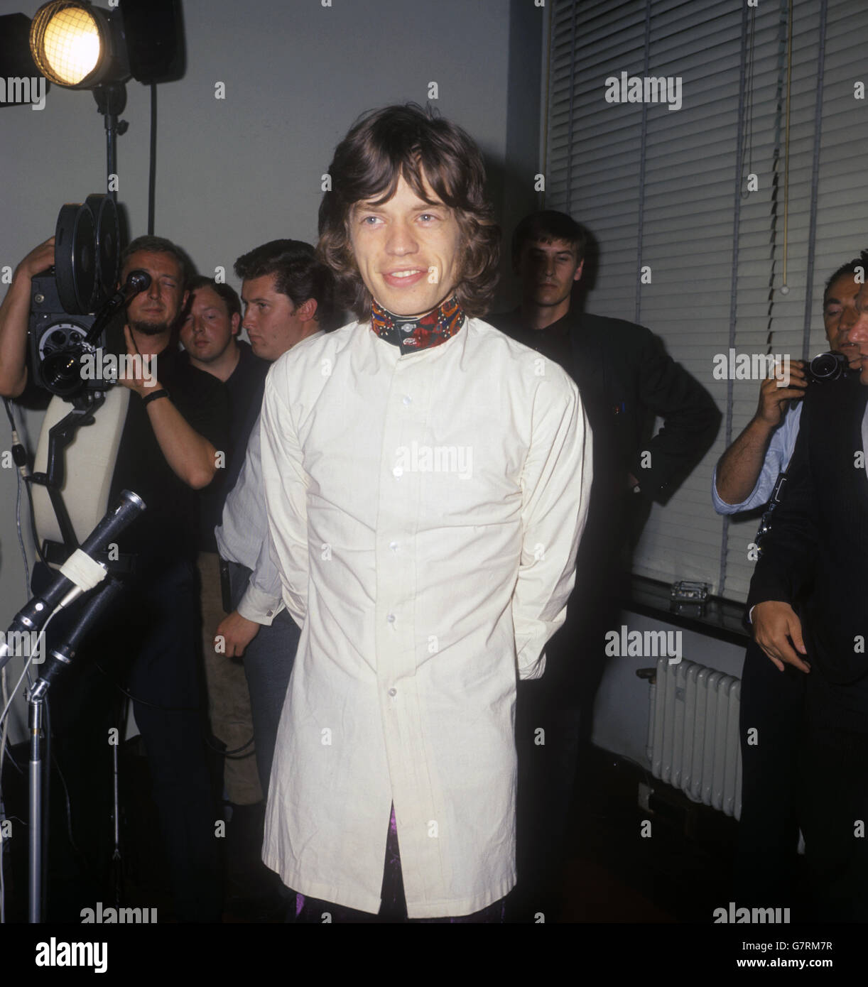 Mick Jagger, dei Rolling Stones, in pantalone satinato viola, giacca a camicia biancastra con colletto e polsino ricamati rosso, giallo e verde. Sta partecipando a una conferenza stampa di Londra, dove annuncerà la sua condanna alla droga è stata abbattuta. Foto Stock