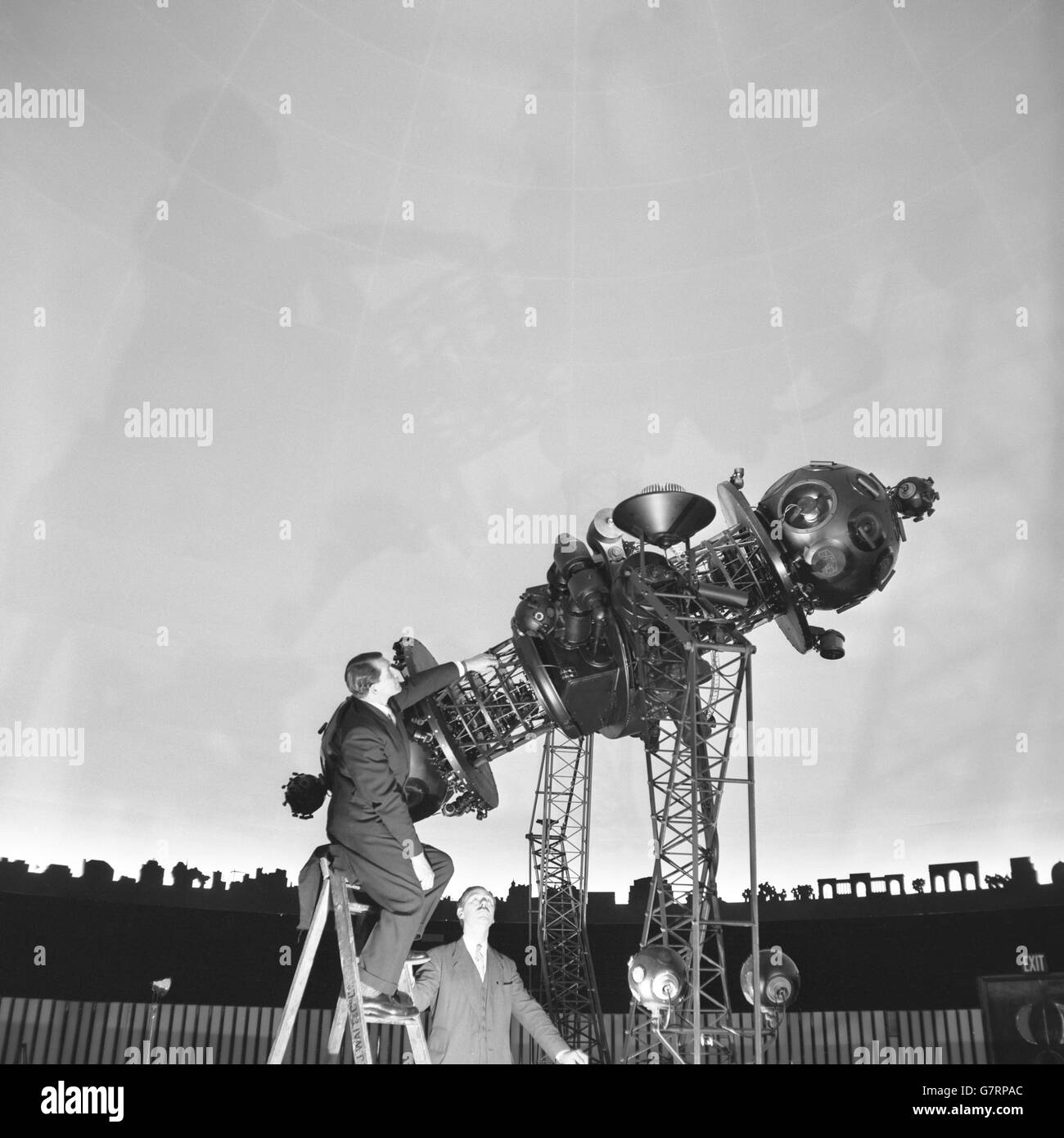 Frank Cousins guarda come il Dr. H. C. King, narratore, controlla lo strumento di proiezione all'interno del nuovo London Planetarium. Le rappresentazioni del cielo, complete di sole, luna e stelle, possono essere proiettate all'interno del tetto a forma di cupola dell'edificio. Gli eventi celesti e le posizioni delle stelle e dei pianeti possono essere mostrati come appaiono in qualsiasi data e da qualsiasi parte della Terra. Il Duca di Edimburgo parteciperà all'inaugurazione il 19 marzo. Foto Stock