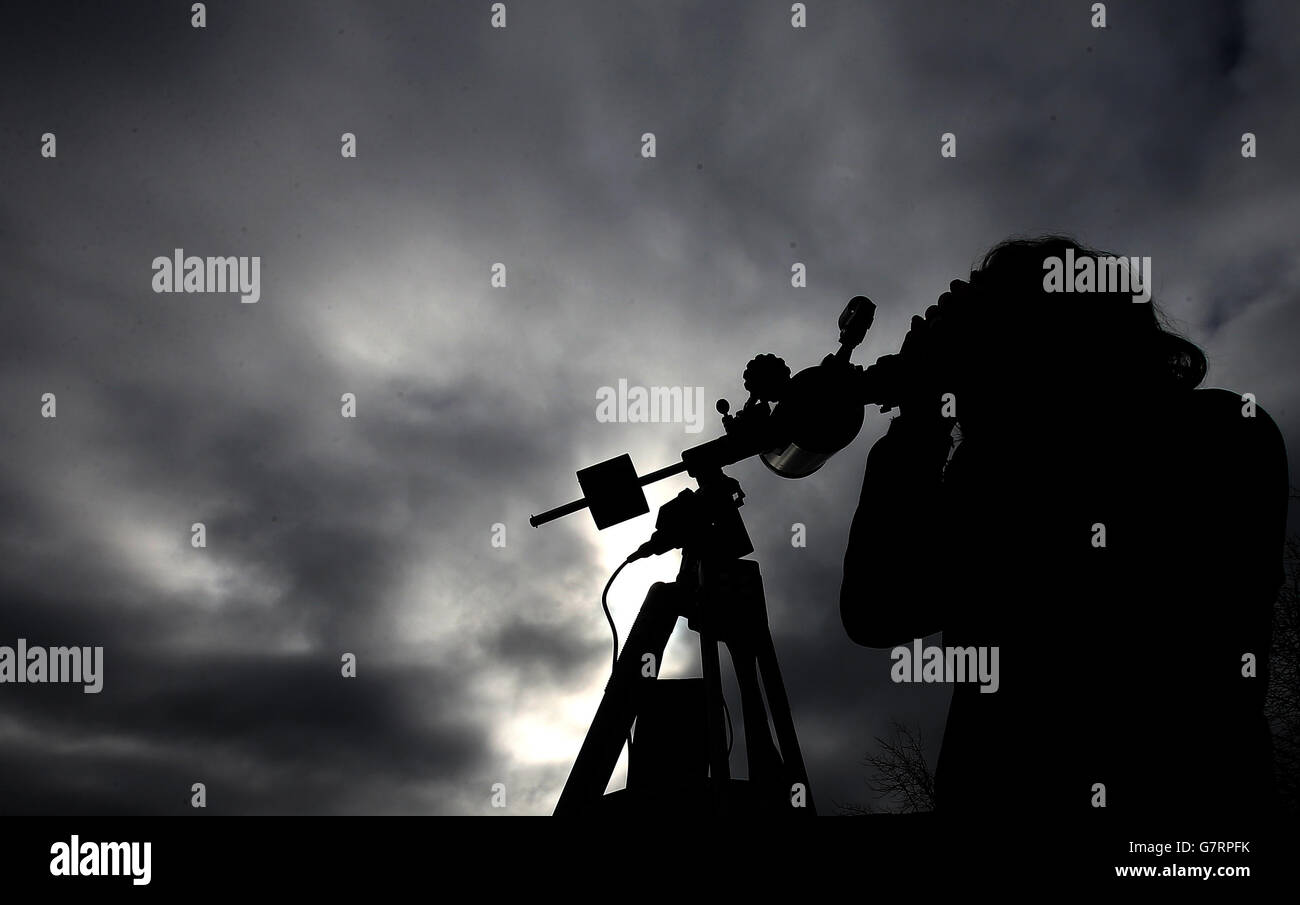 Un uomo vede l'eclissi solare usando il suo telescopio, fuori dal Parlamento scozzese, a Edimburgo. Foto Stock