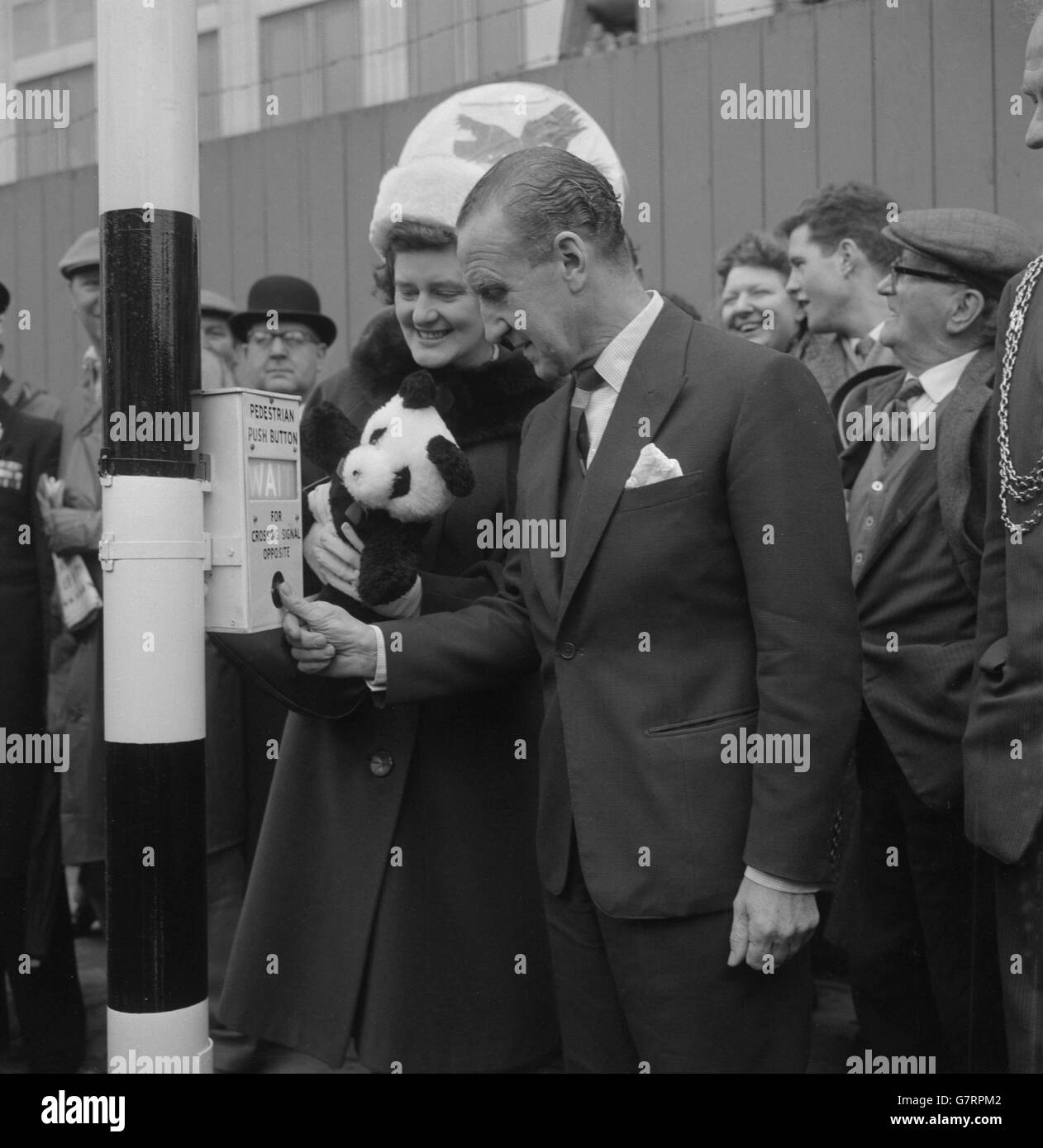 La signora A. C. Dennis, Mayoressa di Lambeth, detiene un giocattolo Panda mentre mi guarda Ernest Marples, ministro dei Trasporti, premere il pulsante per inaugurare la prima traversata pedonale di Panda a Londra a York Road, fuori dalla stazione di Waterloo. I traversini di Panda, da provare per un periodo sperimentale di 12 mesi, hanno luci di avvertimento lampeggianti azionate da comandi a pulsante. Sono dotati di contrassegni a freccia smussati sulla carreggiata e di segnalatori luminosi a strisce nere e ambra. Foto Stock