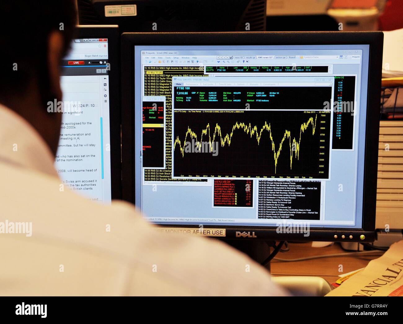 Un lavoratore d'ufficio visualizza un grafico che mostra il movimento di oggi nell'indice FTSE 100, che per la prima volta è salito al di sopra del 7,000-mark nella sua storia. Foto Stock
