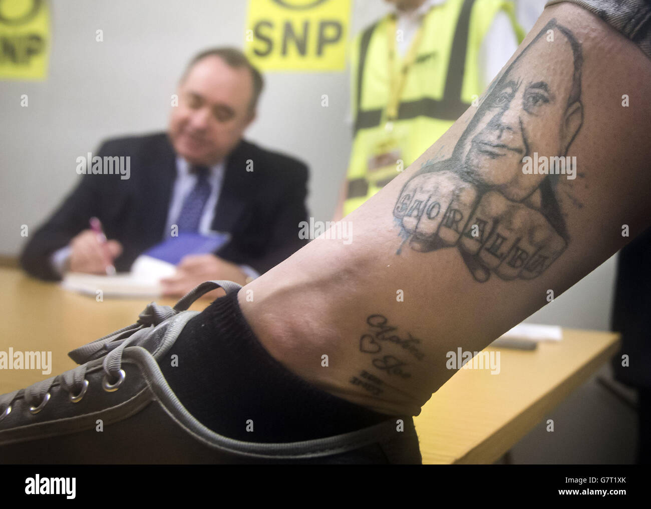 Un sostenitore della SNP mostra fuori il suo tatuaggio dell'ex primo ministro Alex Salmond come Alex Salmond firma una copia del suo libro mentre sul percorso della campagna a Kirkcaldy. Foto Stock