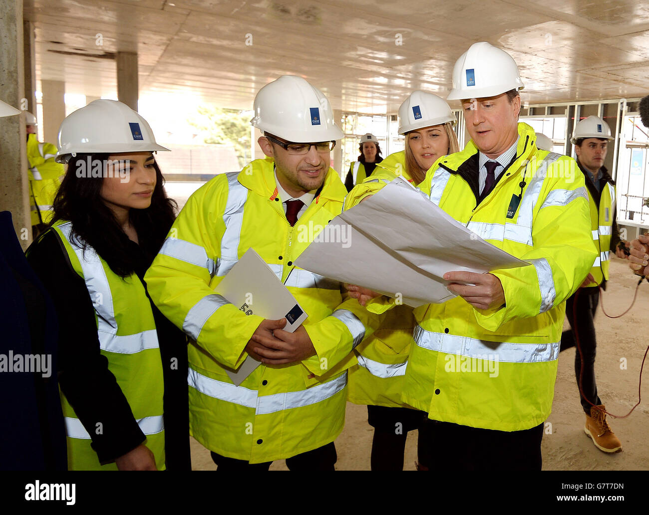 Il primo ministro David Cameron parla con Alex Elias (centro) e il suo fidanzato Nivine El-Sidawi (sinistra), in piedi in quello che sarà il loro appartamento quando completato entro la fine di quest'anno, durante una visita ad un cantiere in cui stanno costruendo appartamenti privati a Isleworth, Londra occidentale. Foto Stock