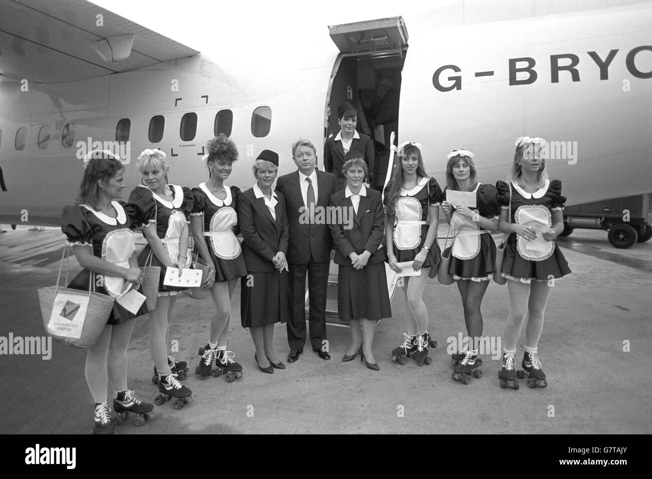 Charles Stuart, presidente e amministratore delegato di Brymon Airways con hostess aerei, fanciulle "francesi" di pattinaggio a rotelle dall'East End di Londra e l'aereo Dash 7 che ha volato da Plymouth per essere il primo volo commerciale di Bryman Airway per il nuovo aeroporto di Londra. La compagnia aerea offre sei voli giornalieri per Parigi dall'aeroporto che ha aperto oggi nel riformato London Docks. Foto Stock