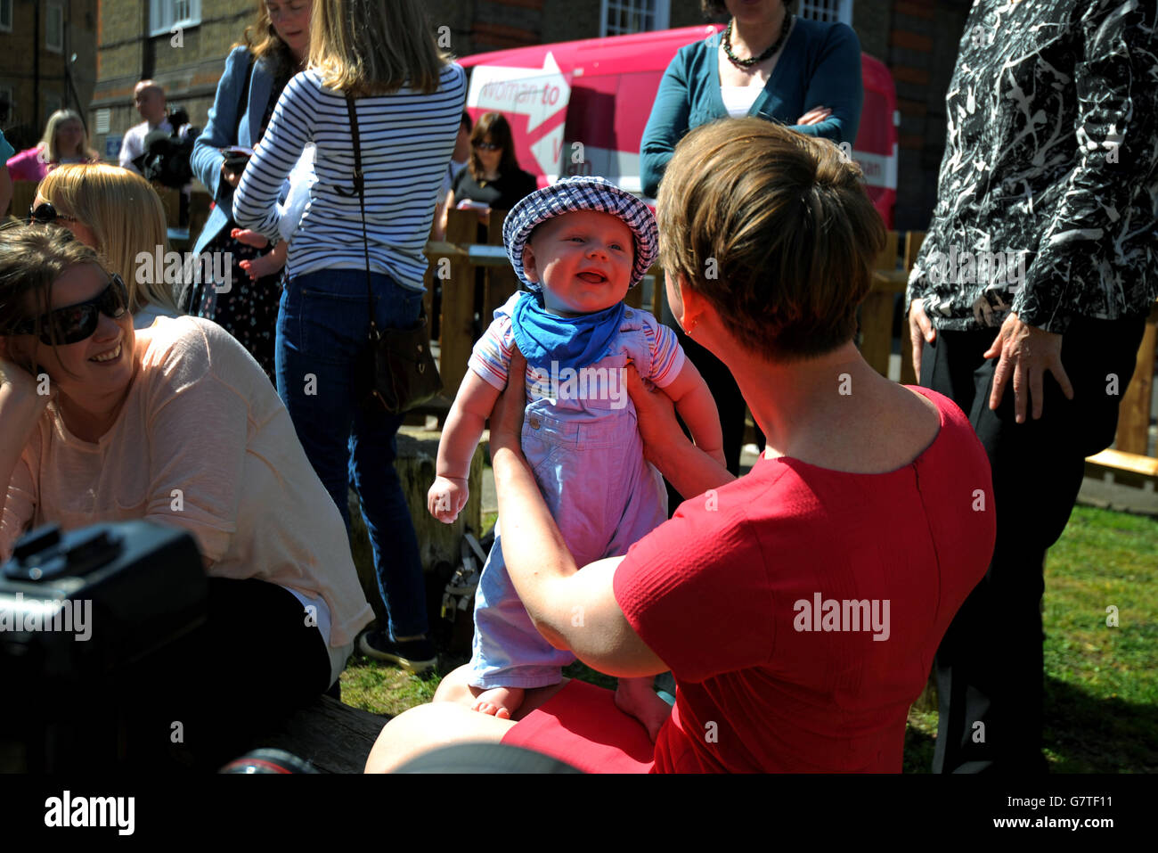 Yvette Cooper tiene il bambino Janosch mentre parla con i genitori al lancio del manifesto delle donne del lavoro al vivaio dei giardini di Stockwell, Londra. Foto Stock