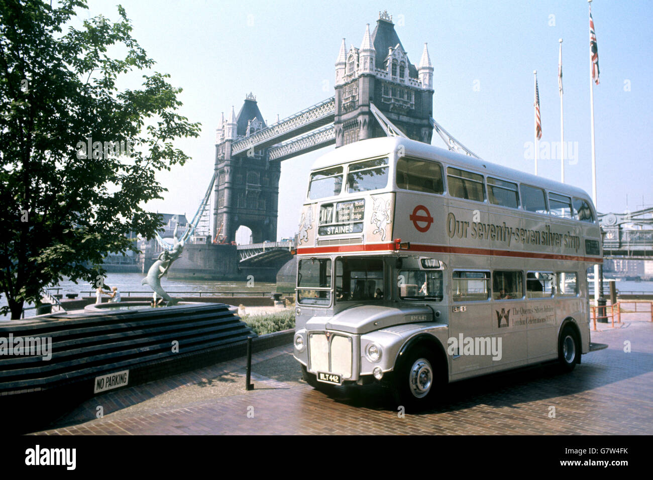 Uno dei 25 autobus a due piani argentati, dipinto appositamente per segnare il Giubileo d'Argento della Regina, si trova di fronte al Tower Bridge. Foto Stock