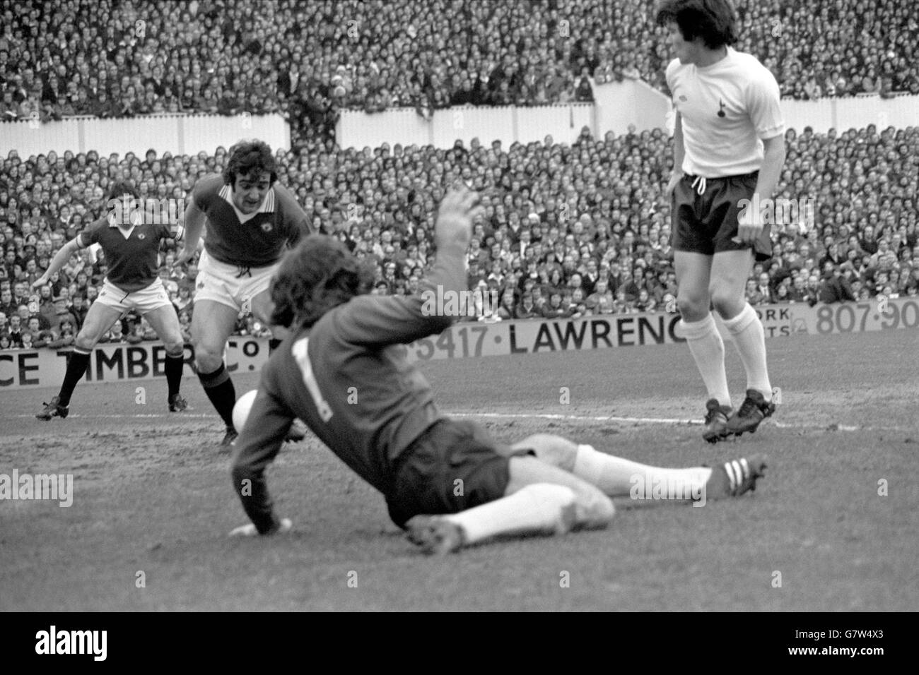 Lou Macari di Manchester United (secondo l) tocca a casa il gol di apertura, guardato dal compagno di squadra Stuart Pearson (l) e Tottenham Hotspur portiere Pat Jennings (secondo r) Foto Stock