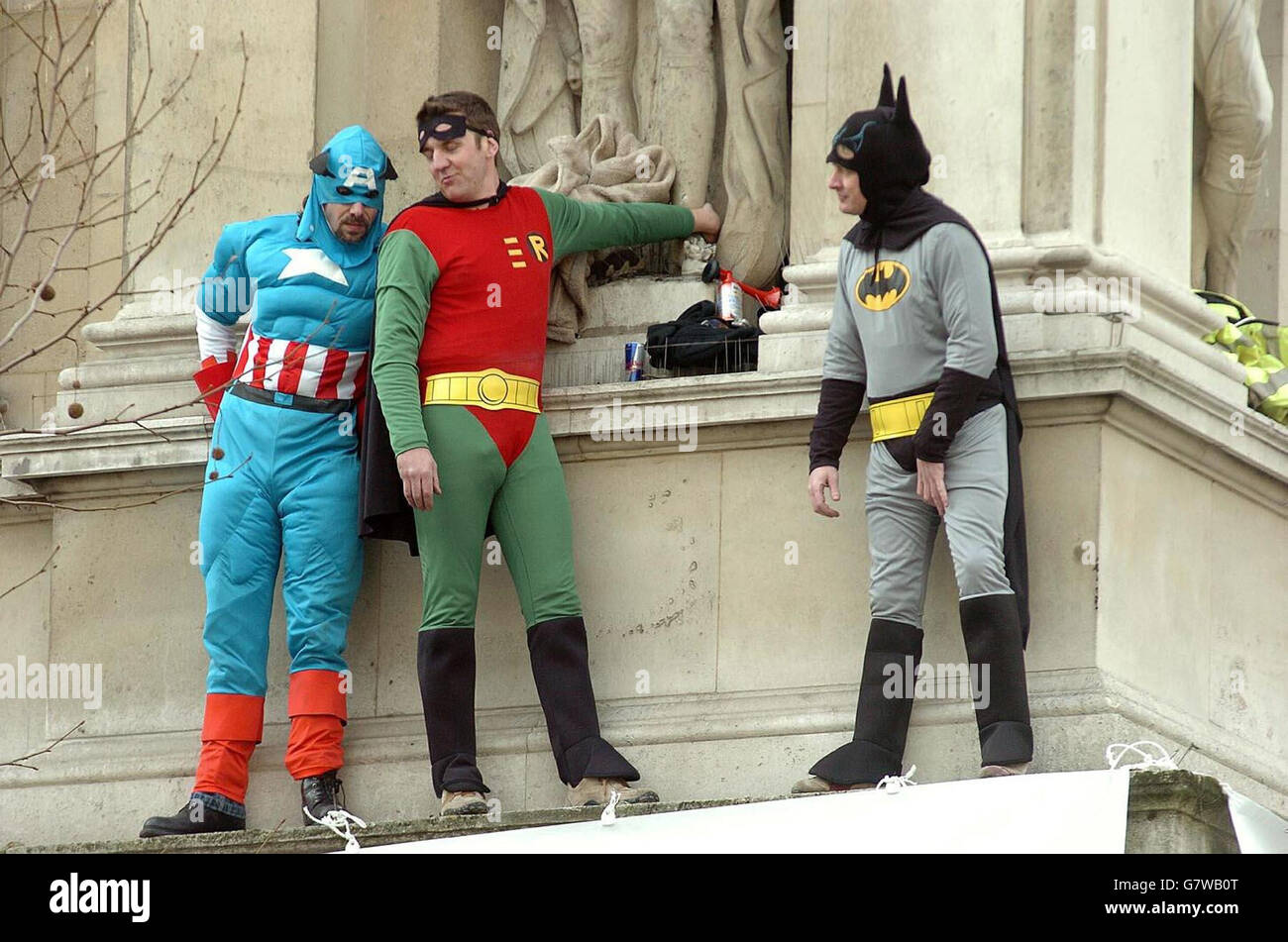 Tre membri della giustizia dei Padri 4 vestiti come supereroi Capitano America, Batman e Robin su una sporgenza del Ministero degli Esteri, sopra l'incrocio di Whitehall e Downing Street. Foto Stock