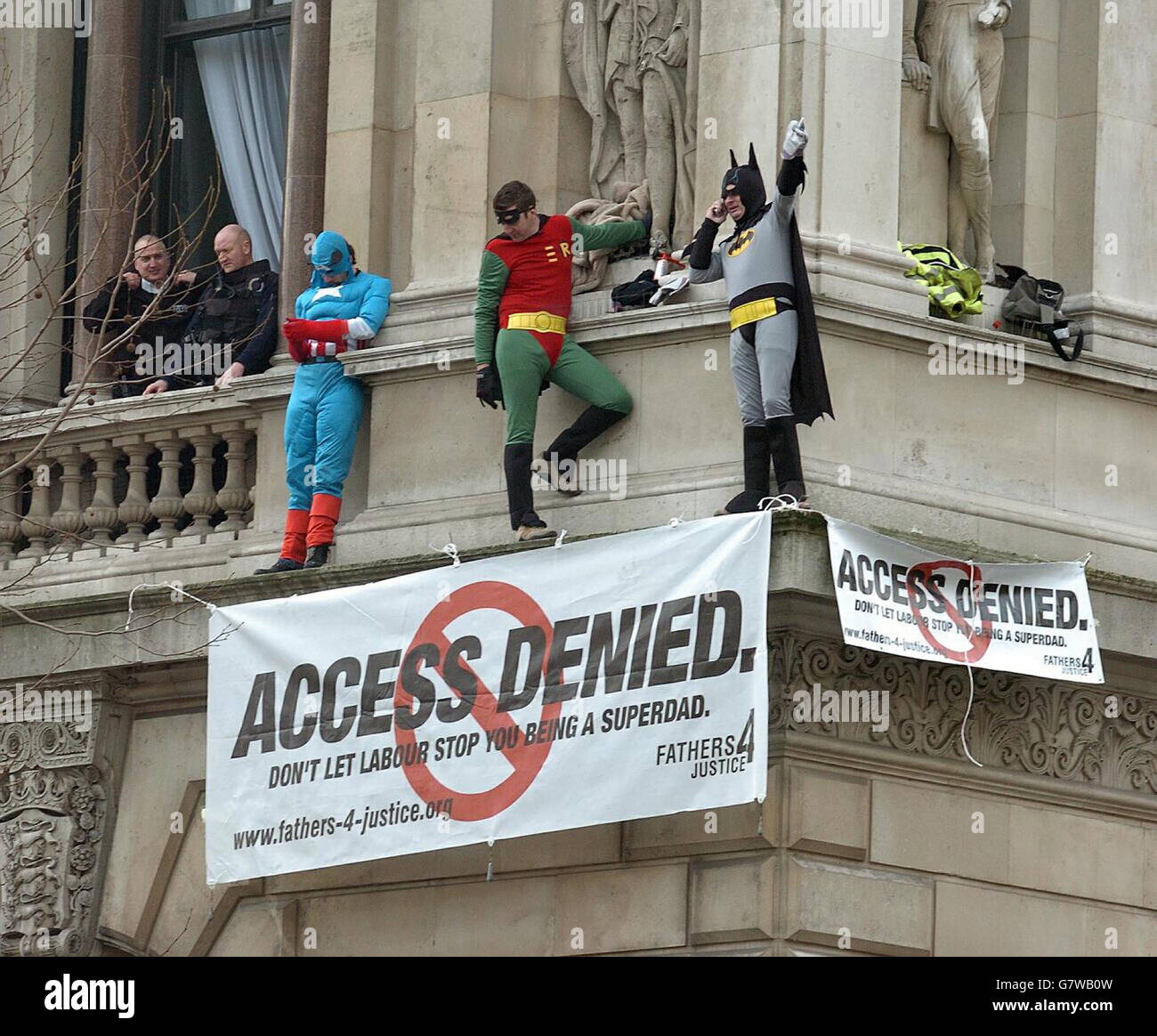 Tre membri della giustizia dei Padri 4 vestiti come supereroi Capitano America, Batman e Robin su una sporgenza del Ministero degli Esteri, sopra l'incrocio di Whitehall e Downing Street. Foto Stock