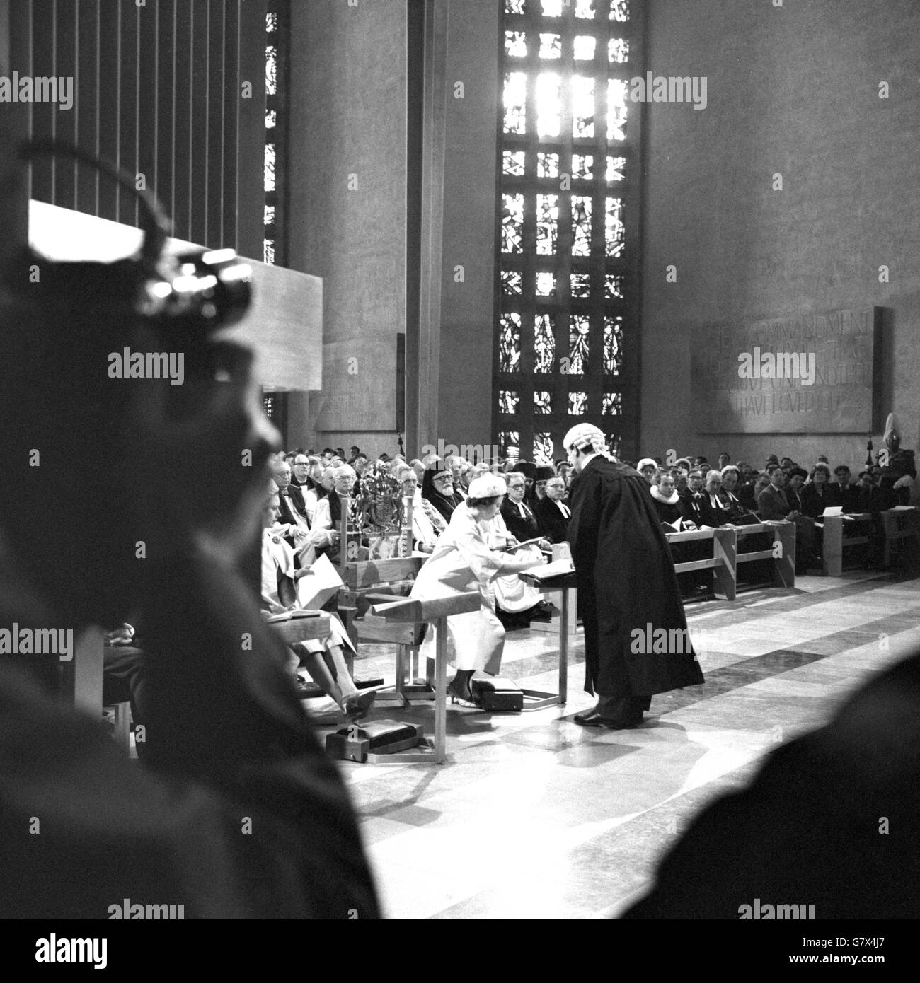La Regina Elisabetta II firma la sentenza di Consacrazione che le viene offerta dal Reggistrar durante la consacrazione della nuova Cattedrale di Coventry. Foto Stock