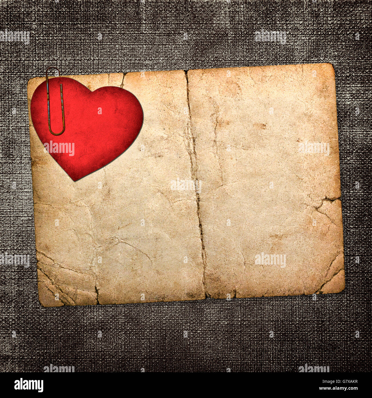 Vecchia scheda di cartone con carta rossa cuore al buio su un sfondo di tessuto Foto Stock