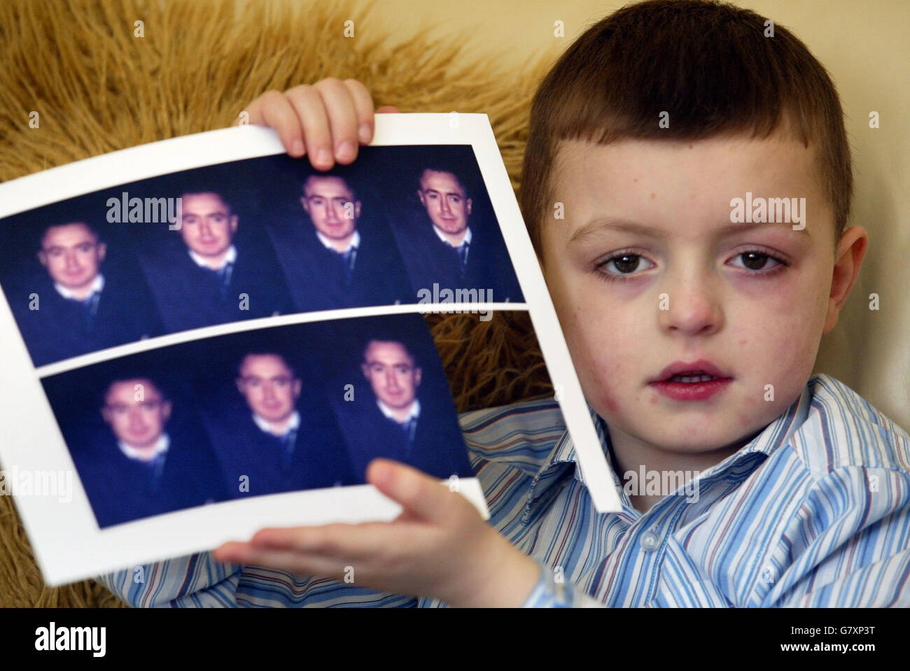 Stephen Montgomery, all'età di 6 anni, figlio della vittima dell'omicidio Stephen Montgomery, 34 anni, conserva una foto del padre nella sua casa Ardoyne. Il sig. Montgomery è stato trovato inconscio con lesioni alla testa vicino alla locanda della Giamaica e alla sua casa nel distretto di Ardoyne della città il 13 febbraio e più successivamente è morto in ospedale. Come Robert McCartney, la vittima dell'omicidio dell'IRA ha ucciso due settimane prima, il padre di tre aveva appena lasciato il suo pub locale. Foto Stock