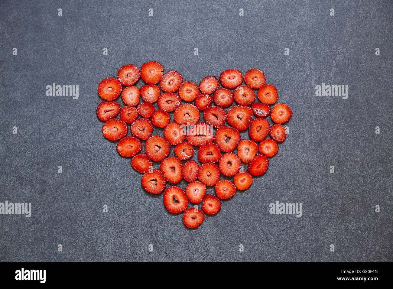 Fragole fresche fetta forma di cuore su sfondo nero Foto Stock