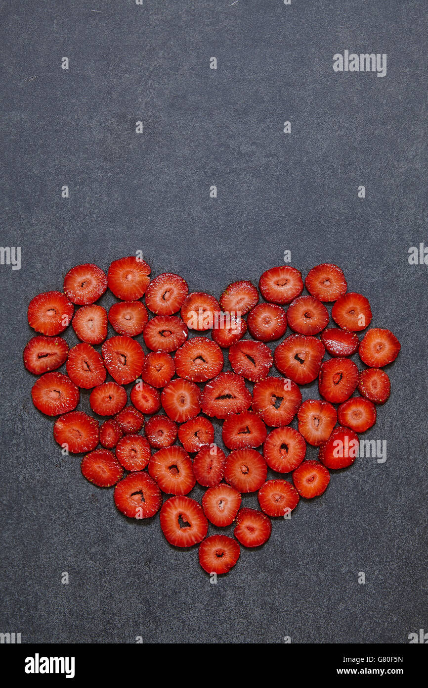 Fragole fresche fetta forma di cuore su sfondo nero Foto Stock