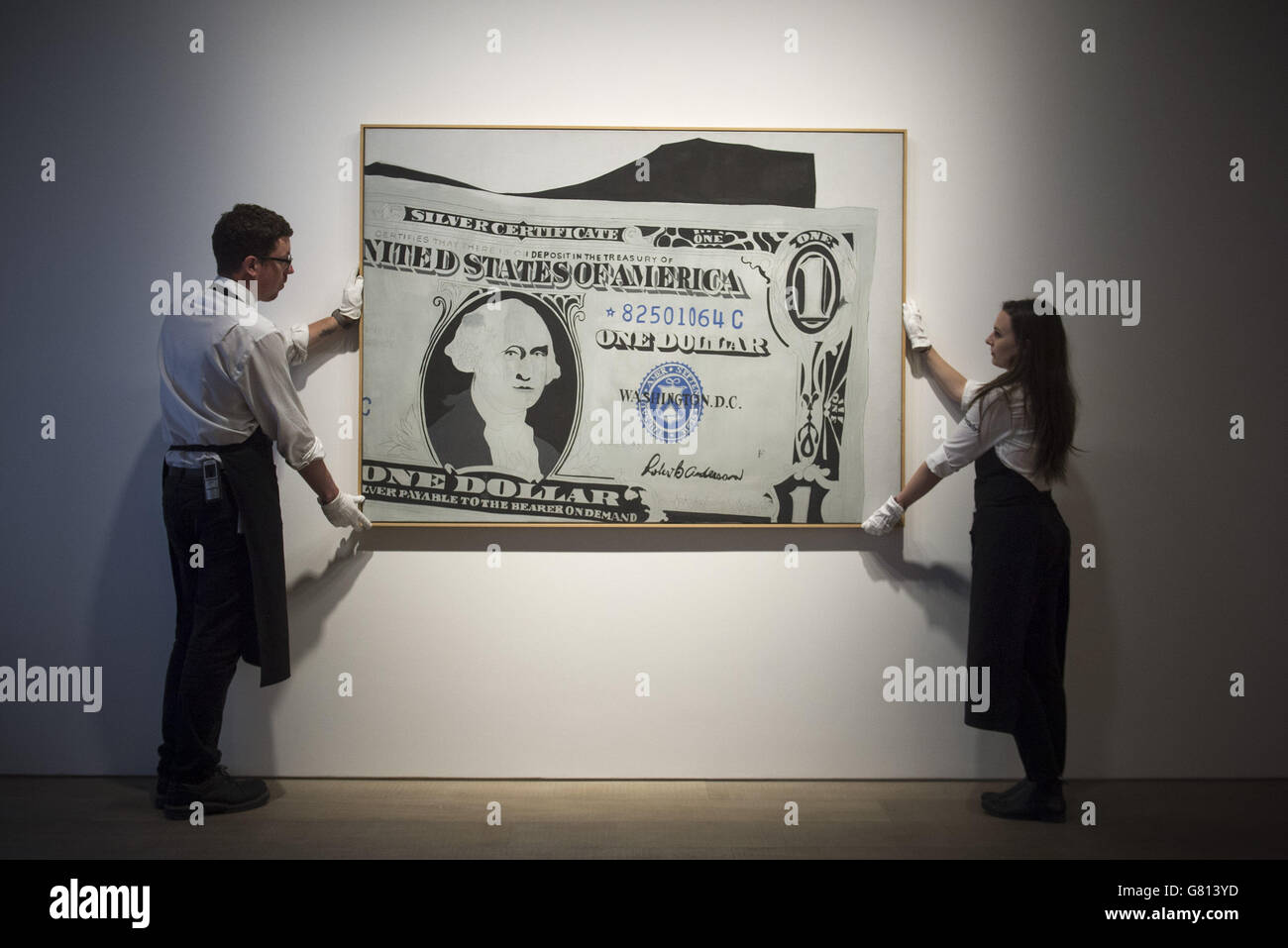 Gli assistenti della galleria aggiustano 'Silver Certificate, 1962' da Andy Warhol, stimato a &Acirc;&Pound;13-18 milioni, durante l'anteprima stampa di 'to the Bearer on Demand', una collezione privata di 21 opere ispirate al Dollaro statunitense da artisti come Andy Warhol a Sotheby's, Londra. Foto Stock