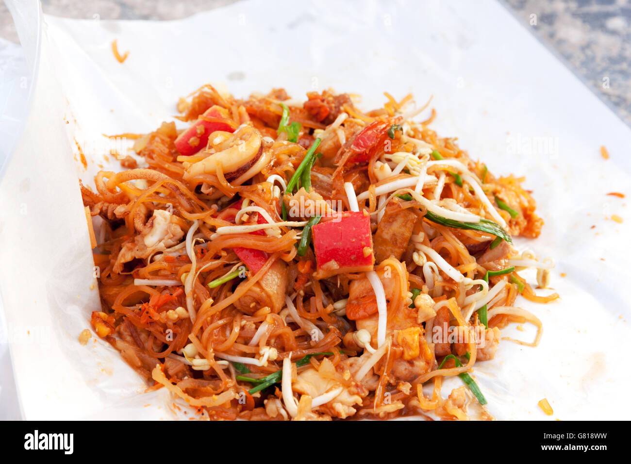 Spaghettini fritti in stile Thai con gamberi. Friggere gli spaghetti con frutti di mare (Pad Thai) cucina tailandese sul colore bianco involucro alimentare. Foto Stock