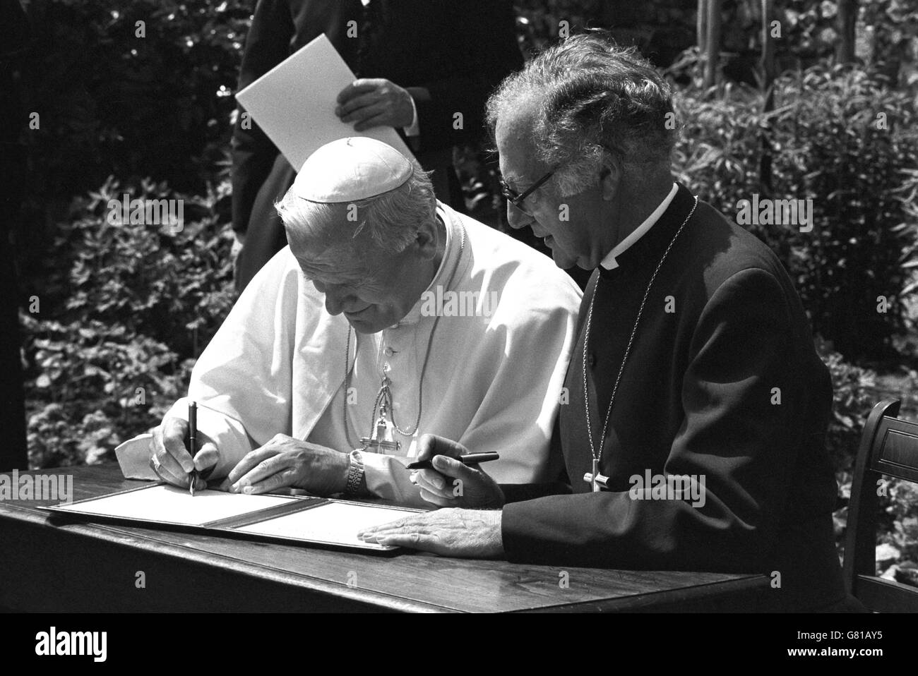 Papa Giovanni Paolo II, seguito dall'arcivescovo di Canterbury, il dottor Robert Runcie firma una dichiarazione al Deanery, per istituire una nuova Commissione Internazionale Anglicano-Romana per esaminare le differenze dottrinali che ancora separano le due chiese. Foto Stock