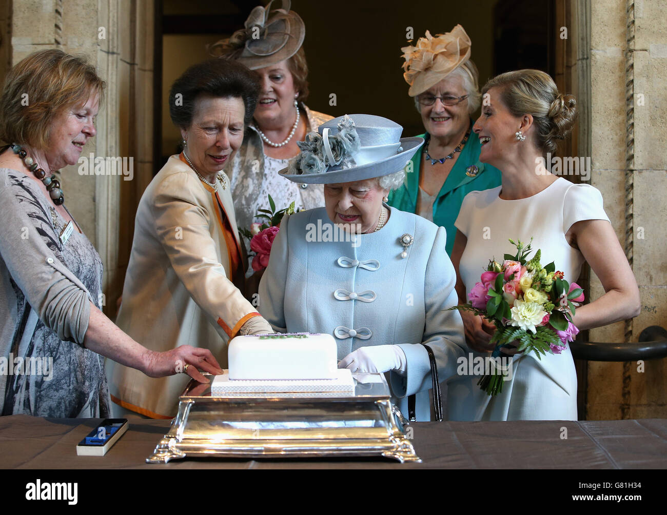 La Principessa reale (2° a sinistra), come la Contessa di Wessex (destra) guarda sopra, aiuta la Regina Elisabetta II a tagliare un Istituto delle Donne che celebra 100 anni di torta al Centenario della riunione annuale della Federazione Nazionale dell'Istituto delle Donne alla Royal Albert Hall alla Royal Albert Hall di Londra. PREMERE ASSOCIAZIONE foto. Data immagine: Giovedì 4 giugno 2015. Vedi la storia della PA ROYAL Queen. Il credito fotografico dovrebbe essere: Chris Jackson/PA Wire Foto Stock